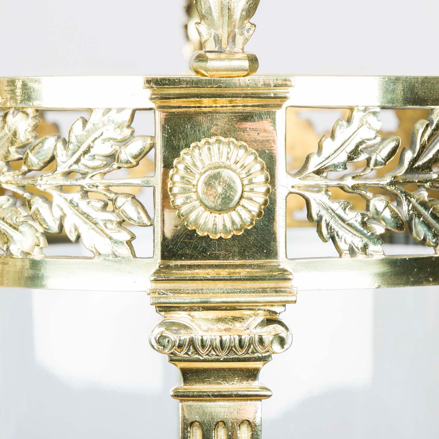 A late 19th century circular glazed brass hall lantern in the neo-classical style, English, circa 1900.

Brass work decorated with Vitruvian scrolls and oak leaf motifs.

Twin light bulb holder, with cut glass hinged door for access to the
