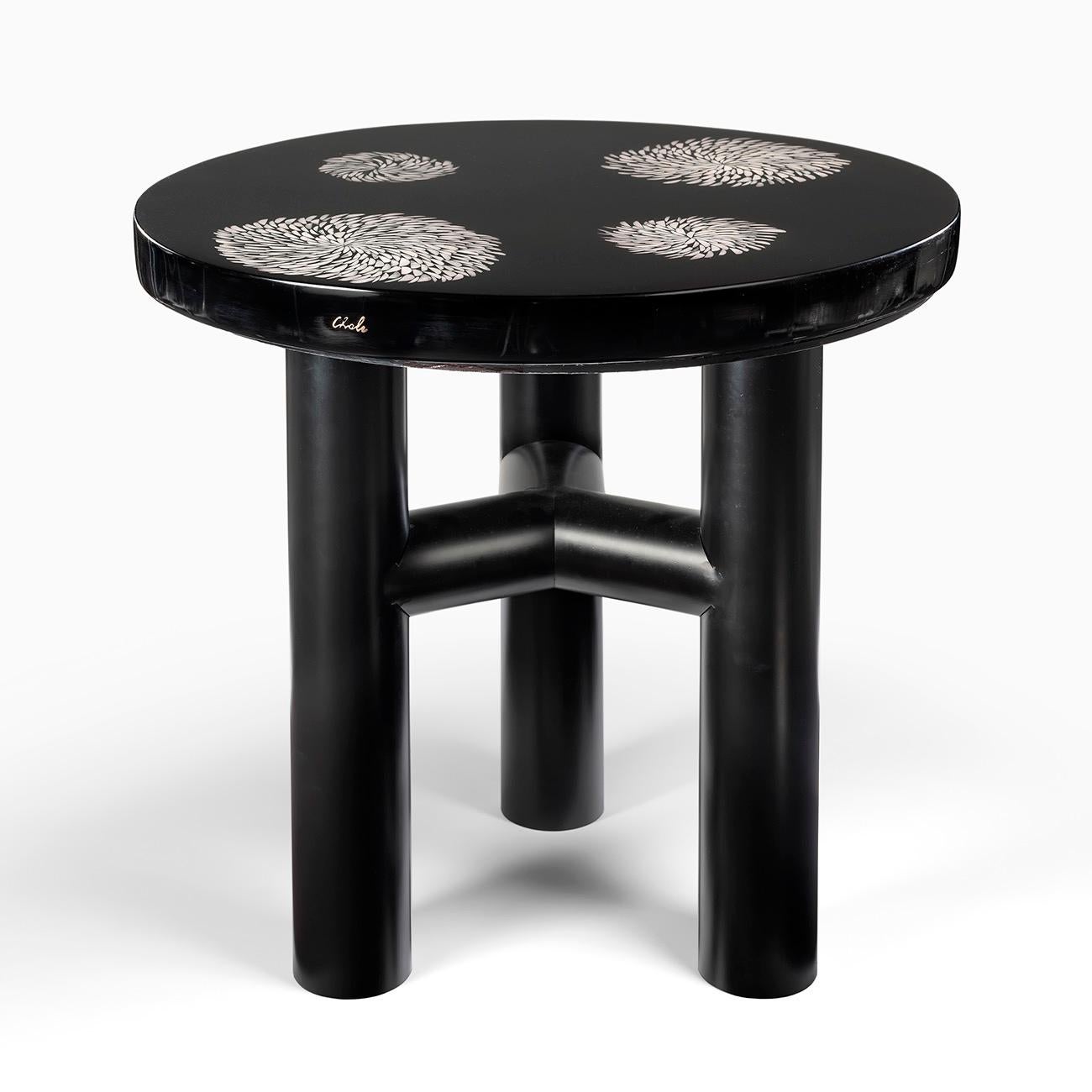 High circular pedestal table, in black resin inlaid with bone marquetry arranged in 4 circles of abstract design.
The top resting on a large tripod foot with round sections, the round section, unique in the designer's work, matches perfectly with