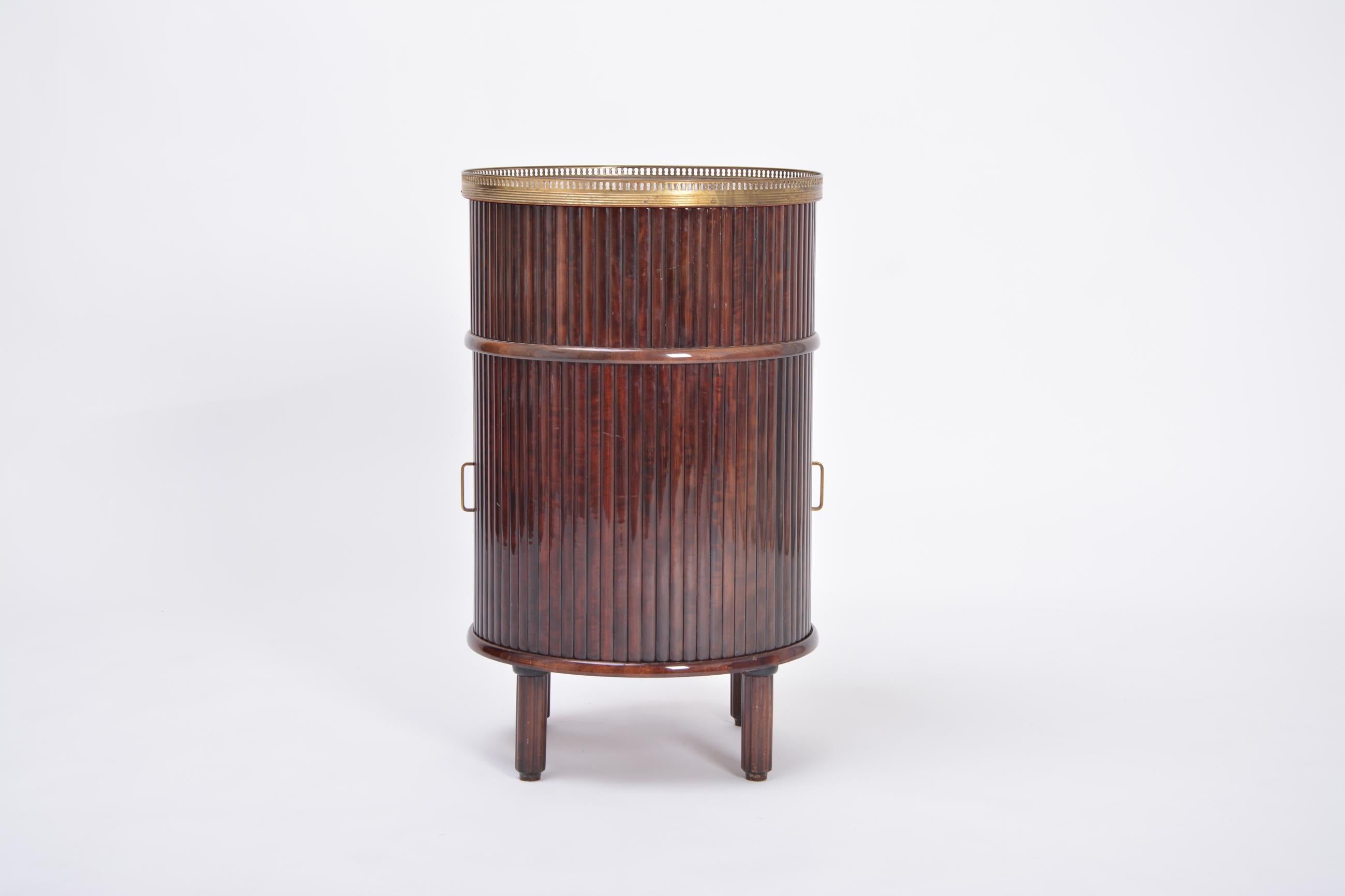 Circular wooden bar cabinet with sliding doors and a swiveling wooden tray produced in Italy in the 1950s. Gorgeous looks thanks to the wooden slats covering the exterieur down to its feet.
The interieur provides recesses for seven bottles.
On top