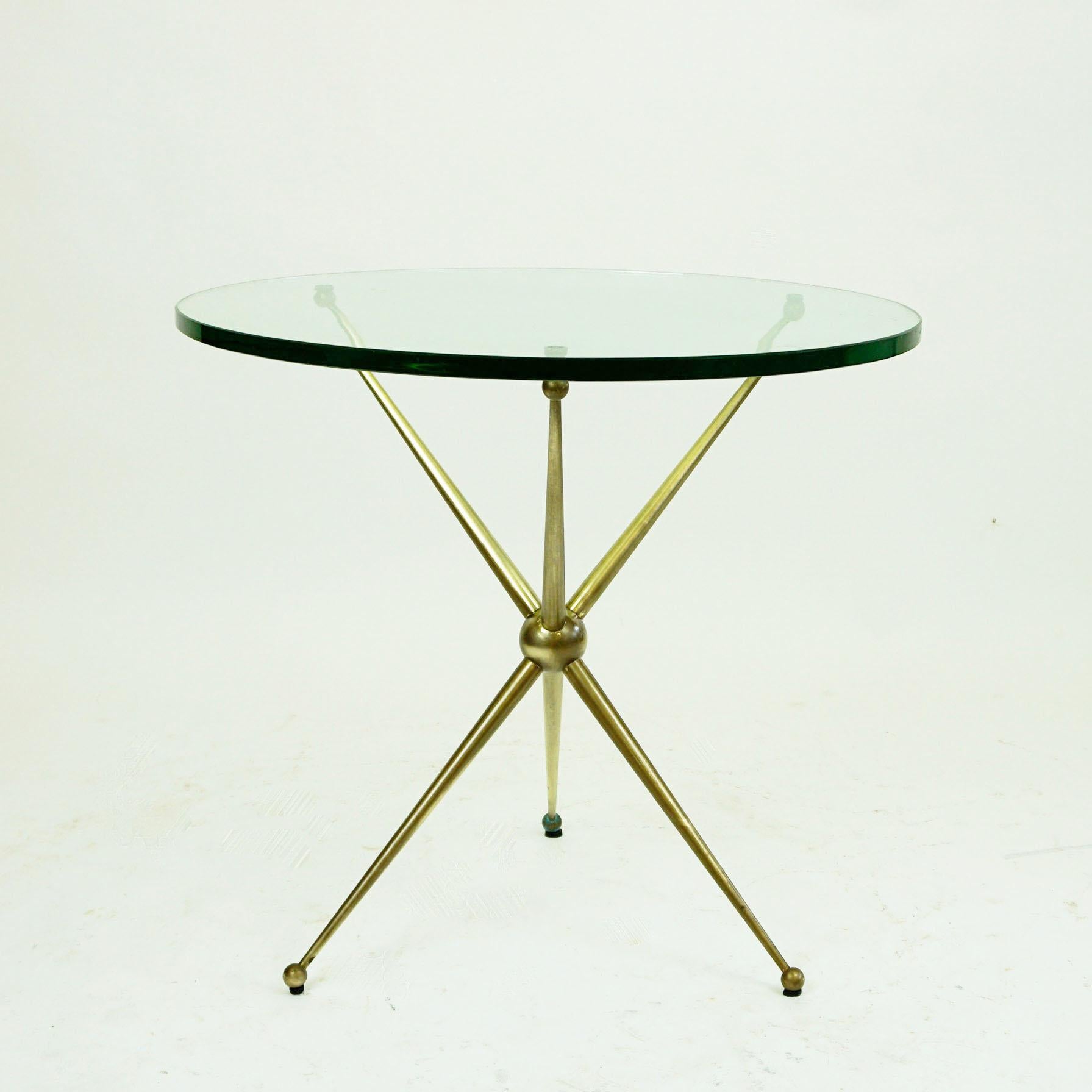 This fantastic midcentury circular brass and glass coffee or side table has been designed and produced in Italy in the 1950s. It features a elegant star shaped tripod brass base and a thick glass top. It´s style is very close to the Furnitures of