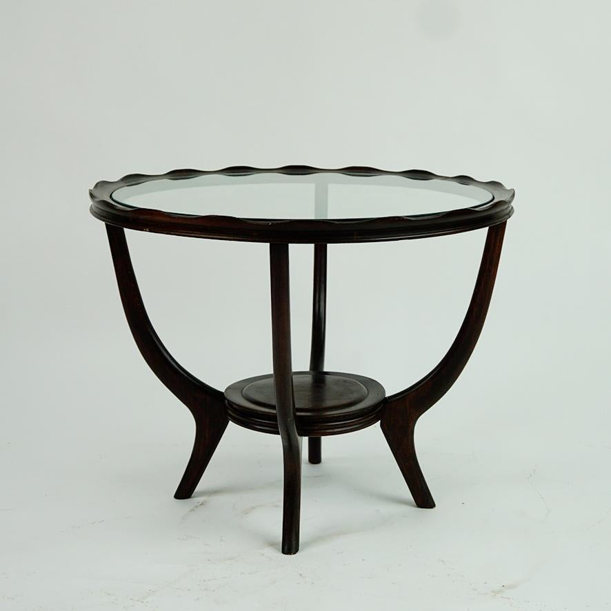 This charming circular mid-century coffee or side table was designed and manufactured in Italy in the 1950s. It's style is very close to coffee tables designed by Carlo di Carli. It features a dark brown stained wooden structure with spider legs and