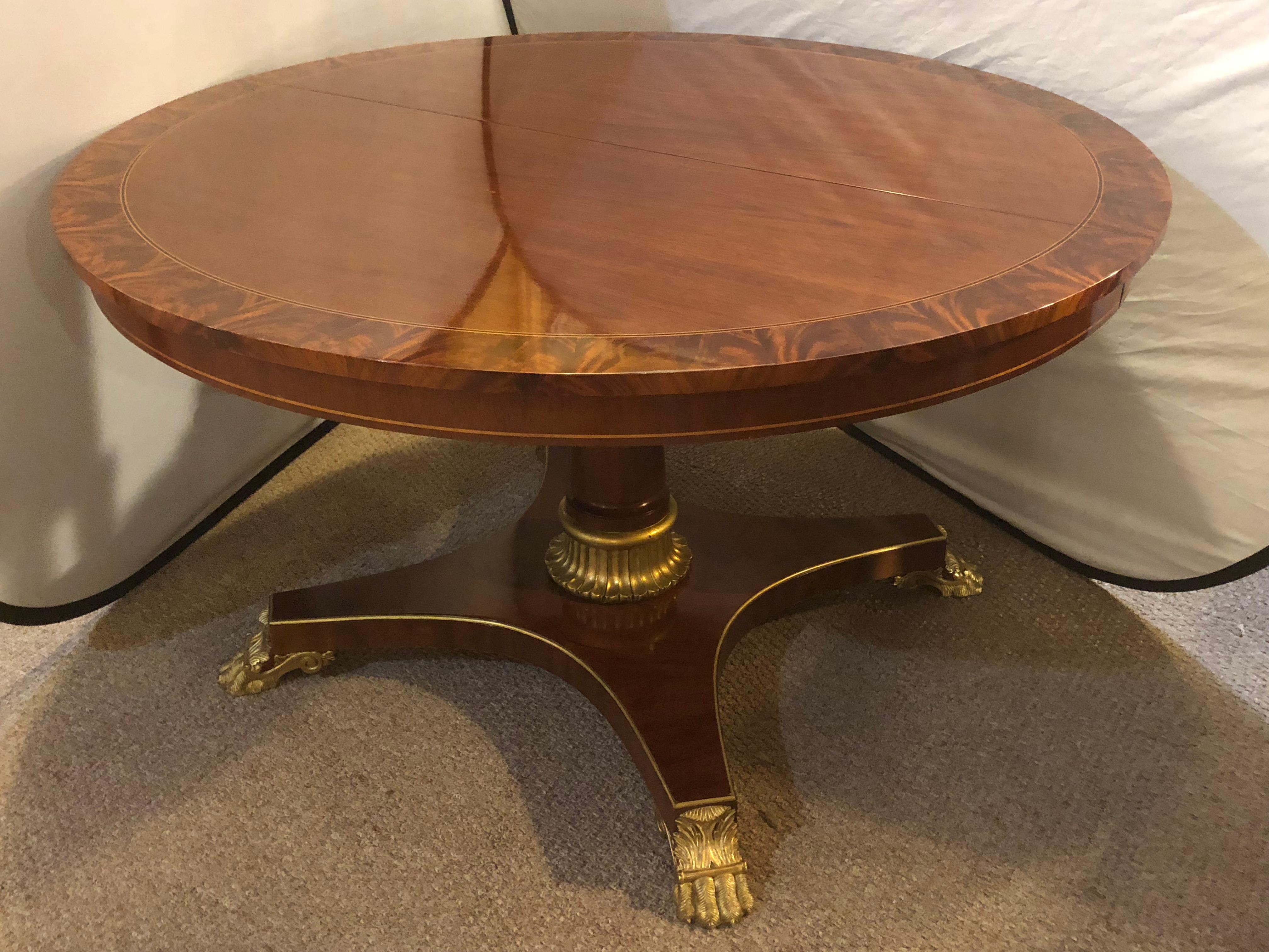 A circular Mid-Century Modern Kindel rosewood banded dining or center table with two leaves. This spectacular dining or center table is part of the Kindel legacy line. The flame mahogany table top having a fine flame mahogany and ebony border