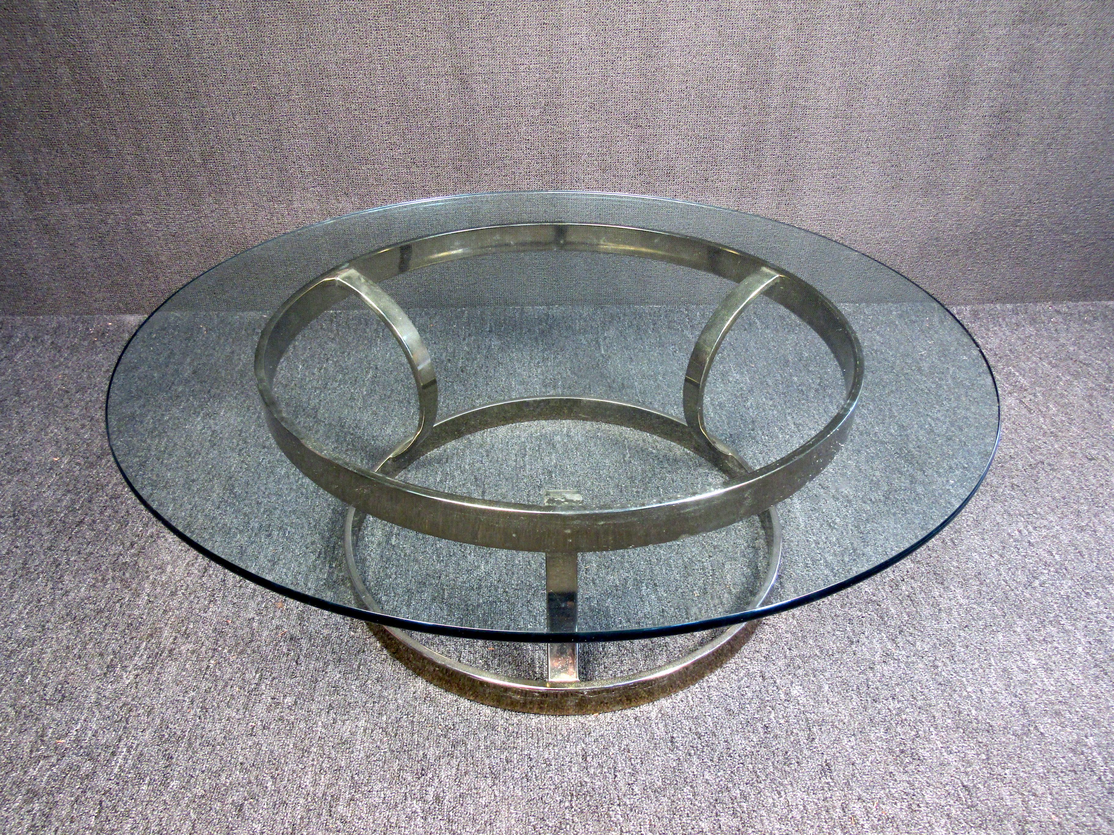 Dieser Couchtisch im Vintage-Stil zeigt einen strahlenden Messingbass durch seine klare Glasplatte. Dieser stilvolle und robuste Mid-Century Modern-Tisch eignet sich perfekt, um in Gesellschaft einen Kaffee oder ein Getränk zu genießen. Bitte