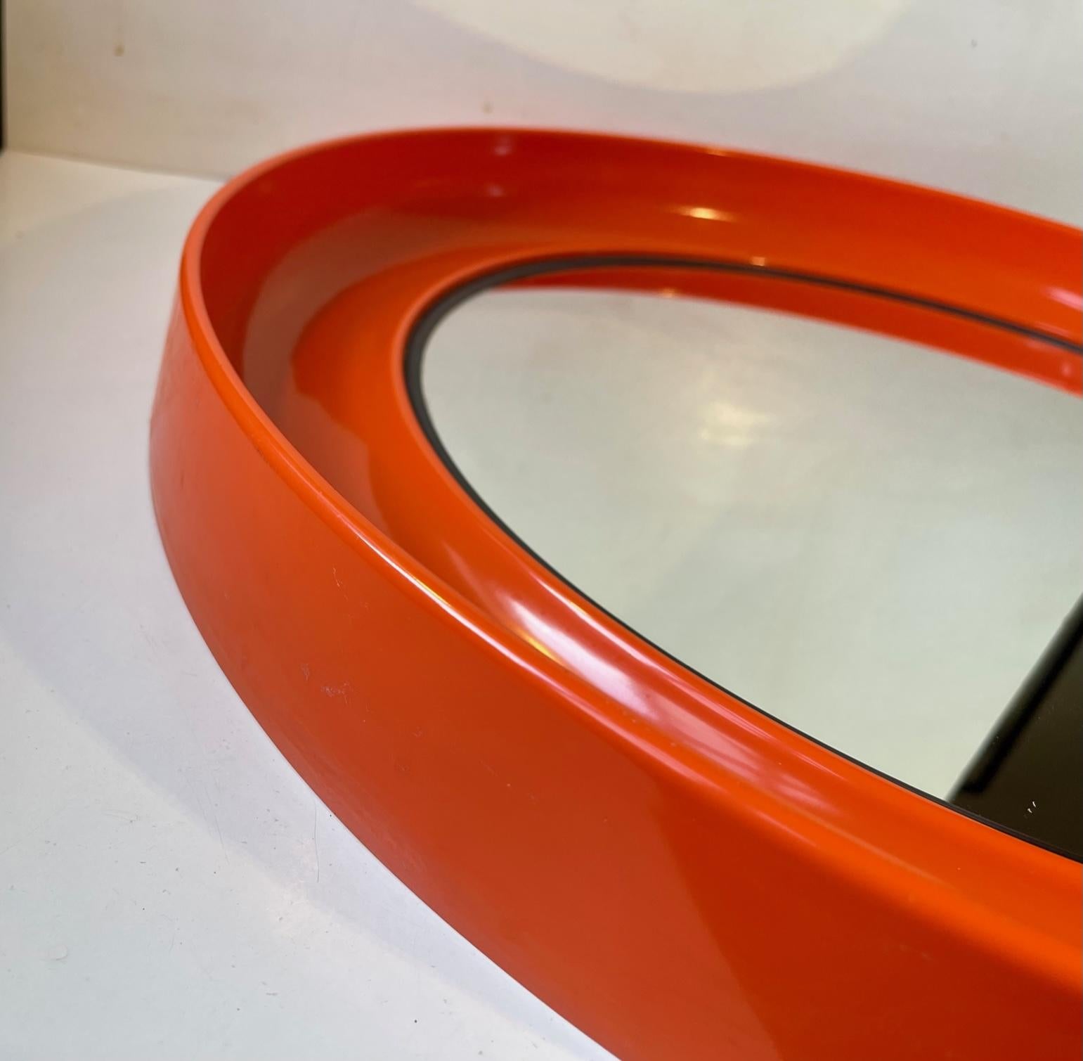 A round orange wall mirror I molded plastic. Beautiful. organic lines and curves. Manufactured in Denmark during the 1970s by Termotex. Anonymous designer. It features a hidden wall mount for a single screw. Measurements: D: 54 cm, Dept: 6 cm.