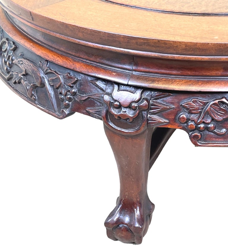 An Exceptional Quality Mid 19th Century Oriental Hardwood Circular coffee table, Of Unusual Form, Having Superbly Figured Top With Decorative Figuring, Over Attractive Well Carved Frieze, Raised On Short Legs With Ball And Claw Feet United By Cross