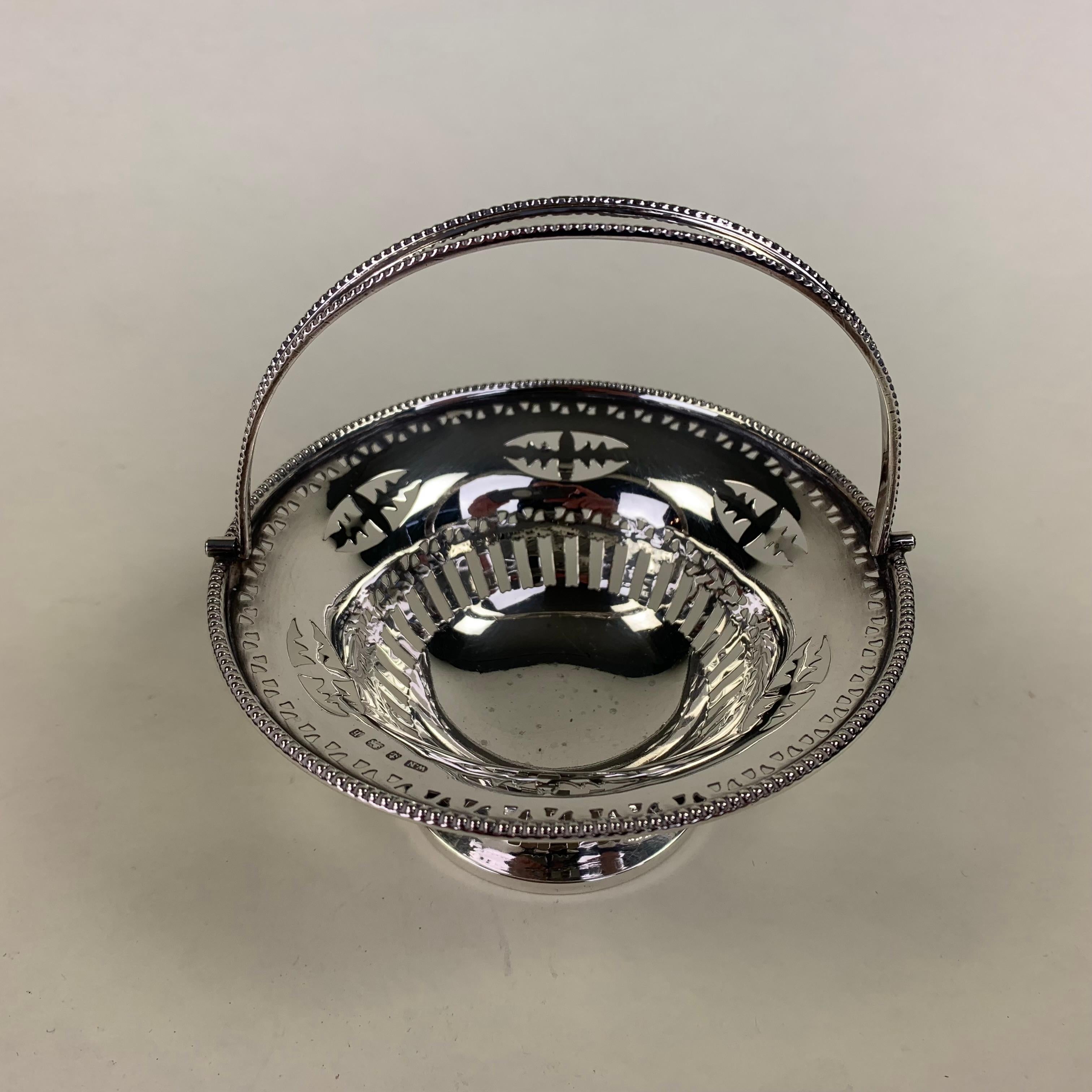 A good quality circular pierced silver sweetmeat dish with hinged loop handle. By William Neale, Birmingham 1907. 96 grams.