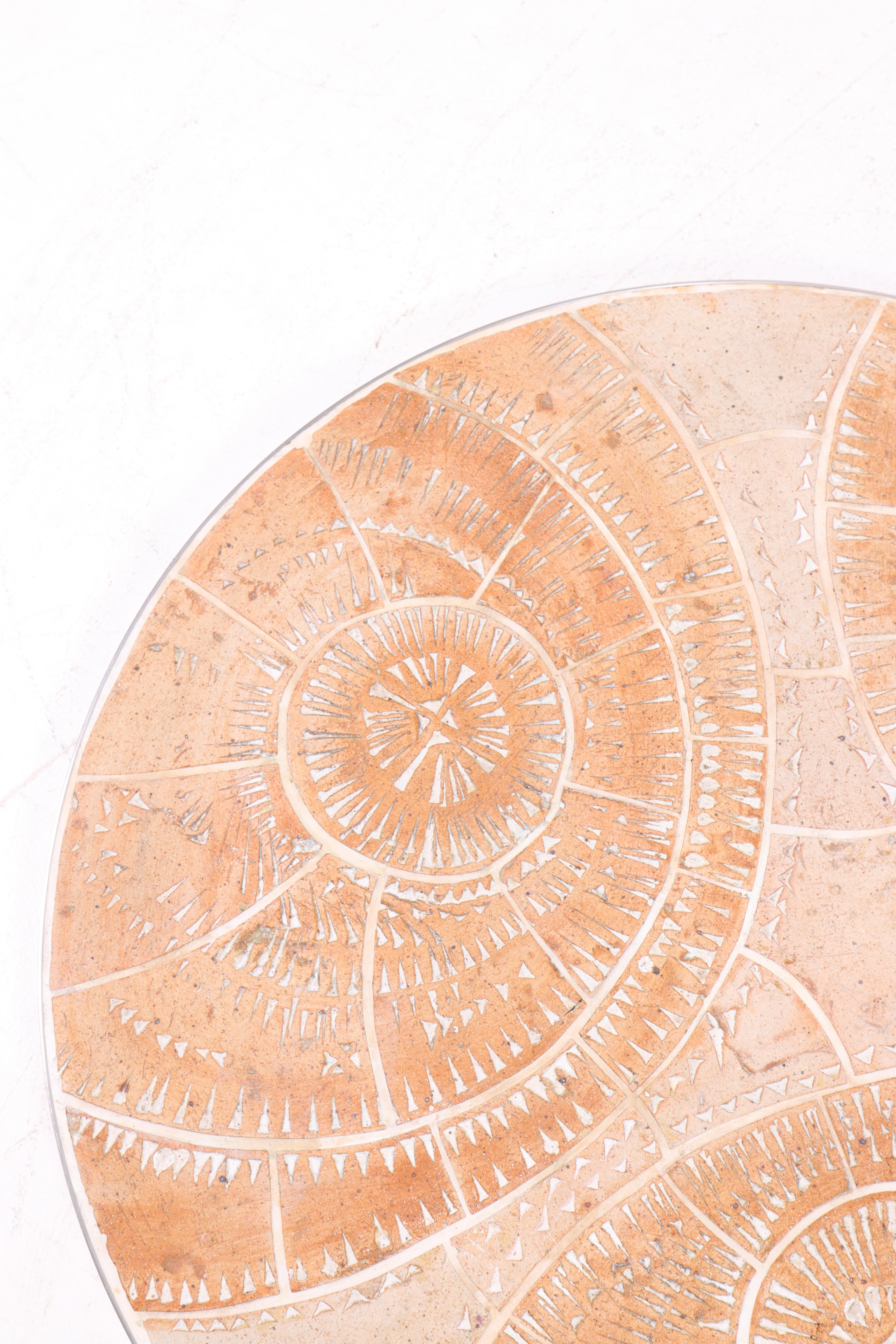 Unique circular relief by Danish ceramic artist Tue Poulsen, created in the 1970s. Executed in ceramic with an organic geometric pattern in relief, the piece presents depth and a vivid surface structure. The warm tones and hand-carved detailing give