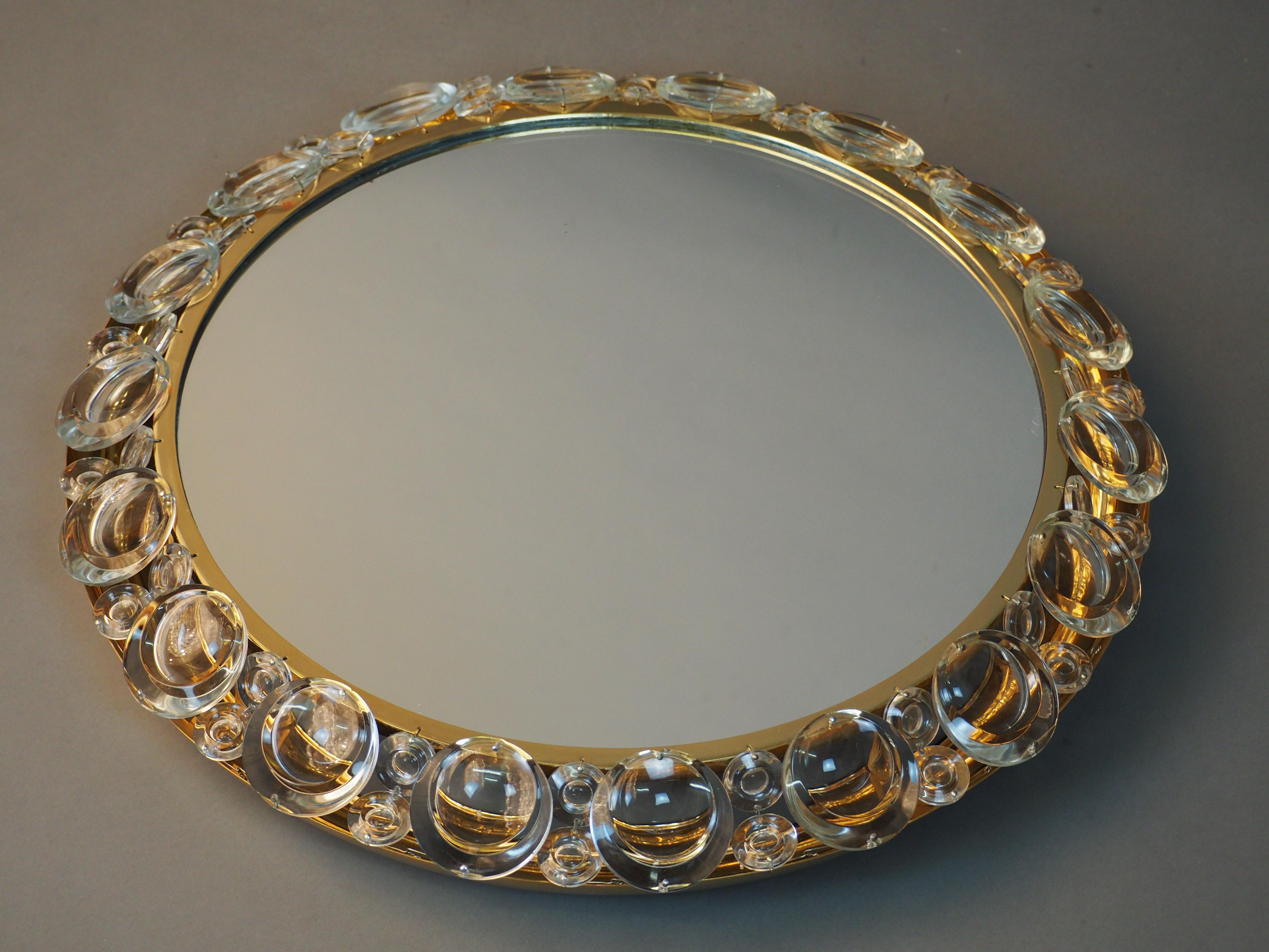 Wonderful illuminated cilcular midcentury mirror by Palwa, Germany, circa 1950s.
Made of high-quality gilt brass frame decorated with lens glasses around.


  