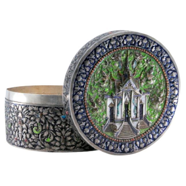 Circular silver box with enameled reliefs in oriental style and Buddhist temple