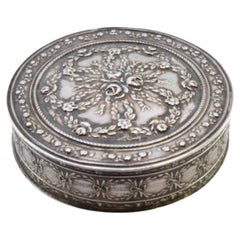 Circular silver box with floral reliefs and a hinged lid