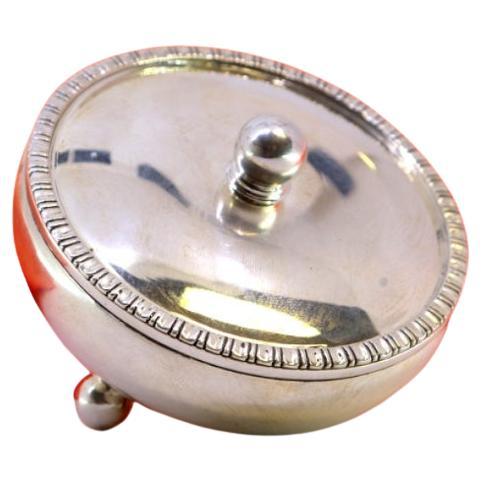 Circular silver box with lid knob, frieze and three spherical feet