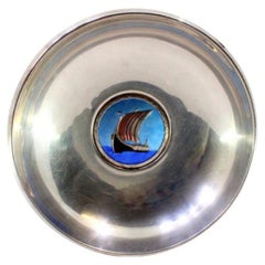 Circular silver cup with a Viking ship enamel frame in the center