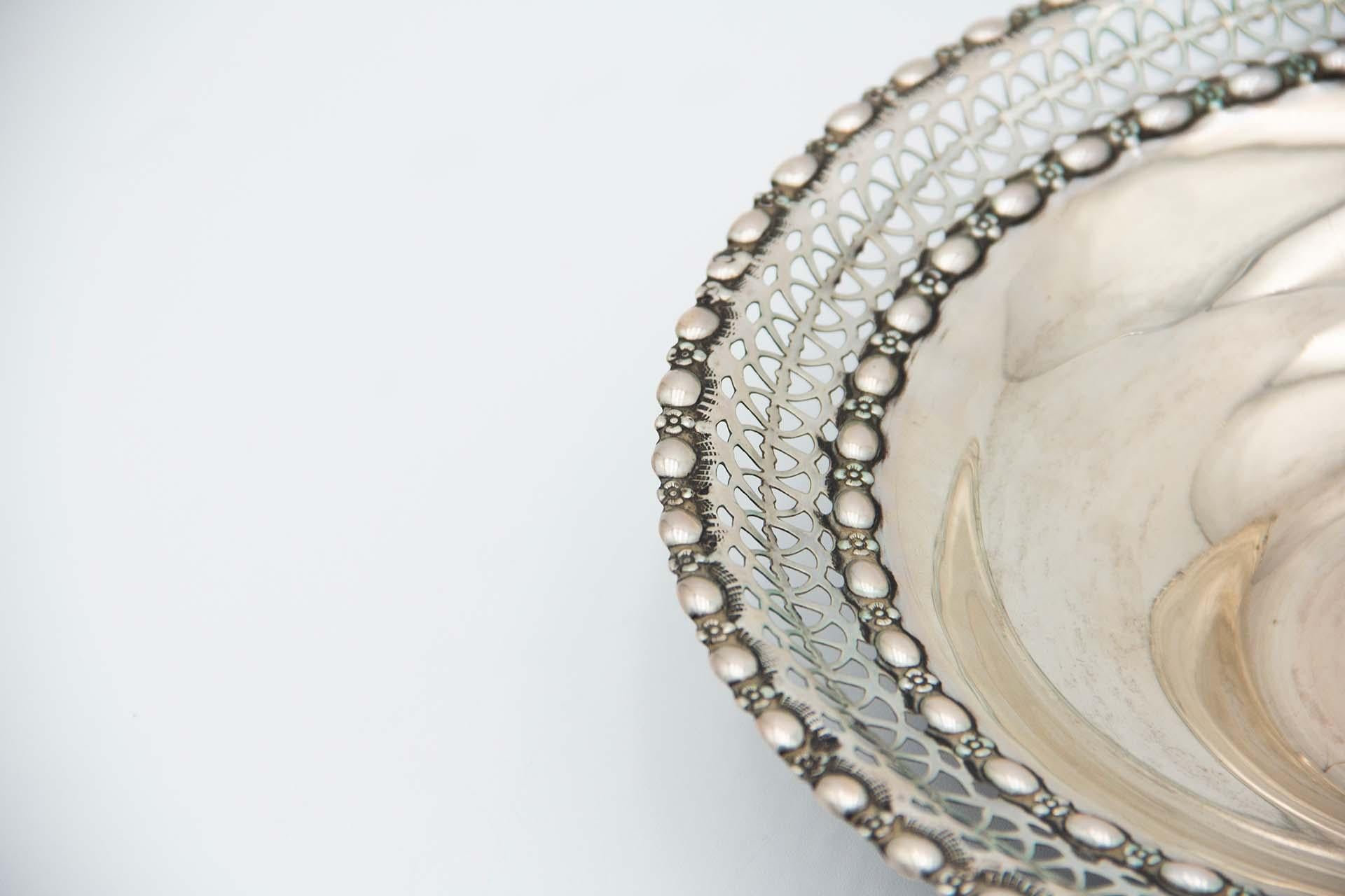 Description: Circular silver fruit bowl with rack. Metal: Silver. Origin: Portuguese. Mark: standing eagle. Weight: 227.56 grams. Dimensions: 25.5cmx5.2cm. Content: 833/1000. Assay Mark: Yes, between 1938 and 1984. Additional information: Good