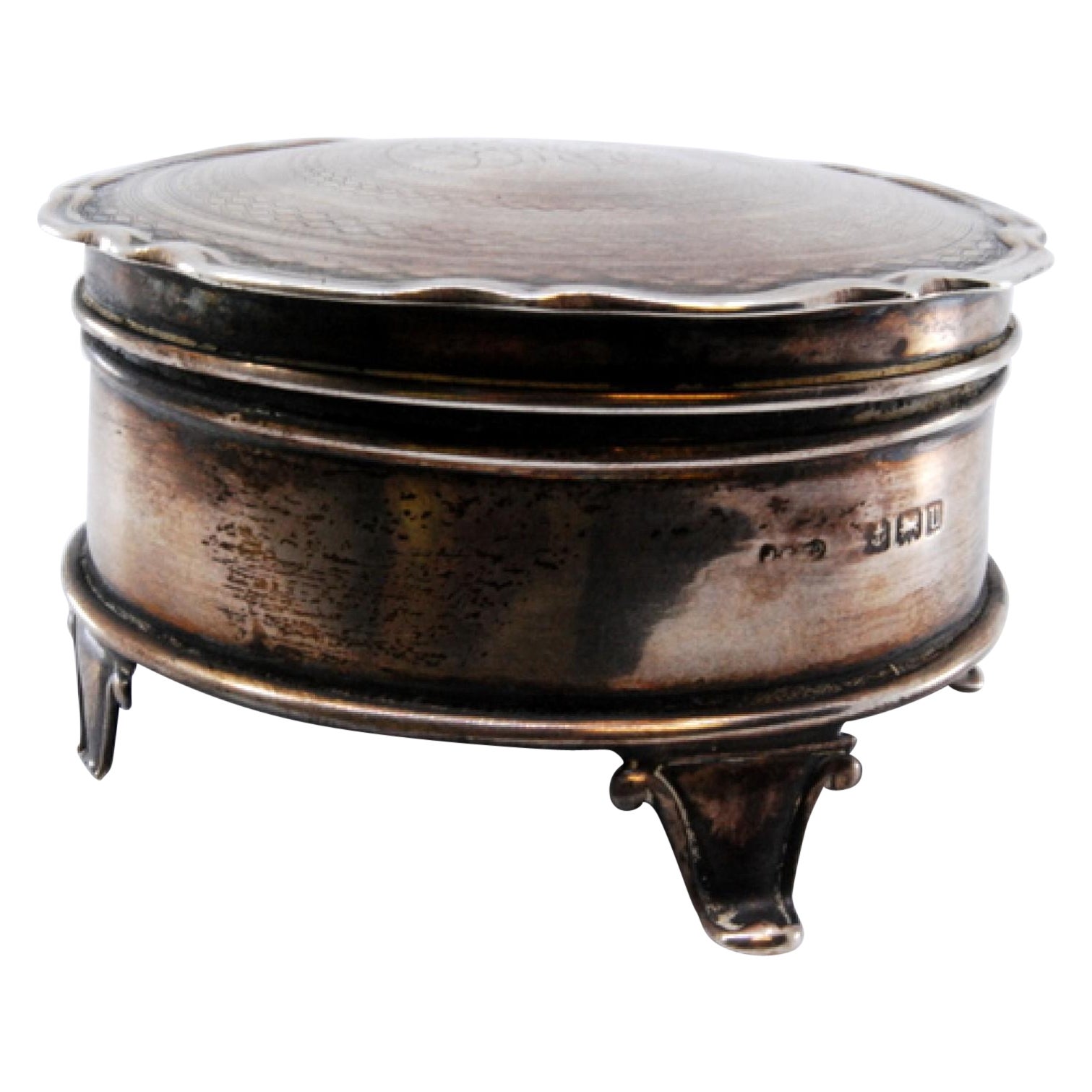 Circular silver jewelry box with engraved plant motifs and raised feet