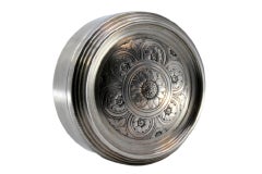 Circular silver jewelry box with floral motifs engraved on the hinged lid