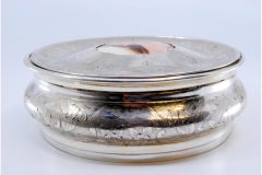 Circular silver jewelry box with plant engravings and enamel lady card