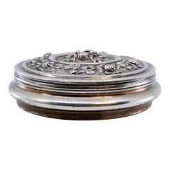 Circular silver jewelry box with reliefs and floral motifs on the removable lid
