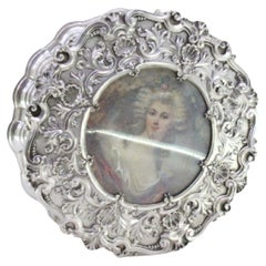 Circular silver jewelry box with shells, scrolls and ancient-lady figure