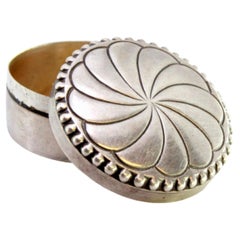 Circular silver pill box with engraved vortex and pearly friezes around the edge