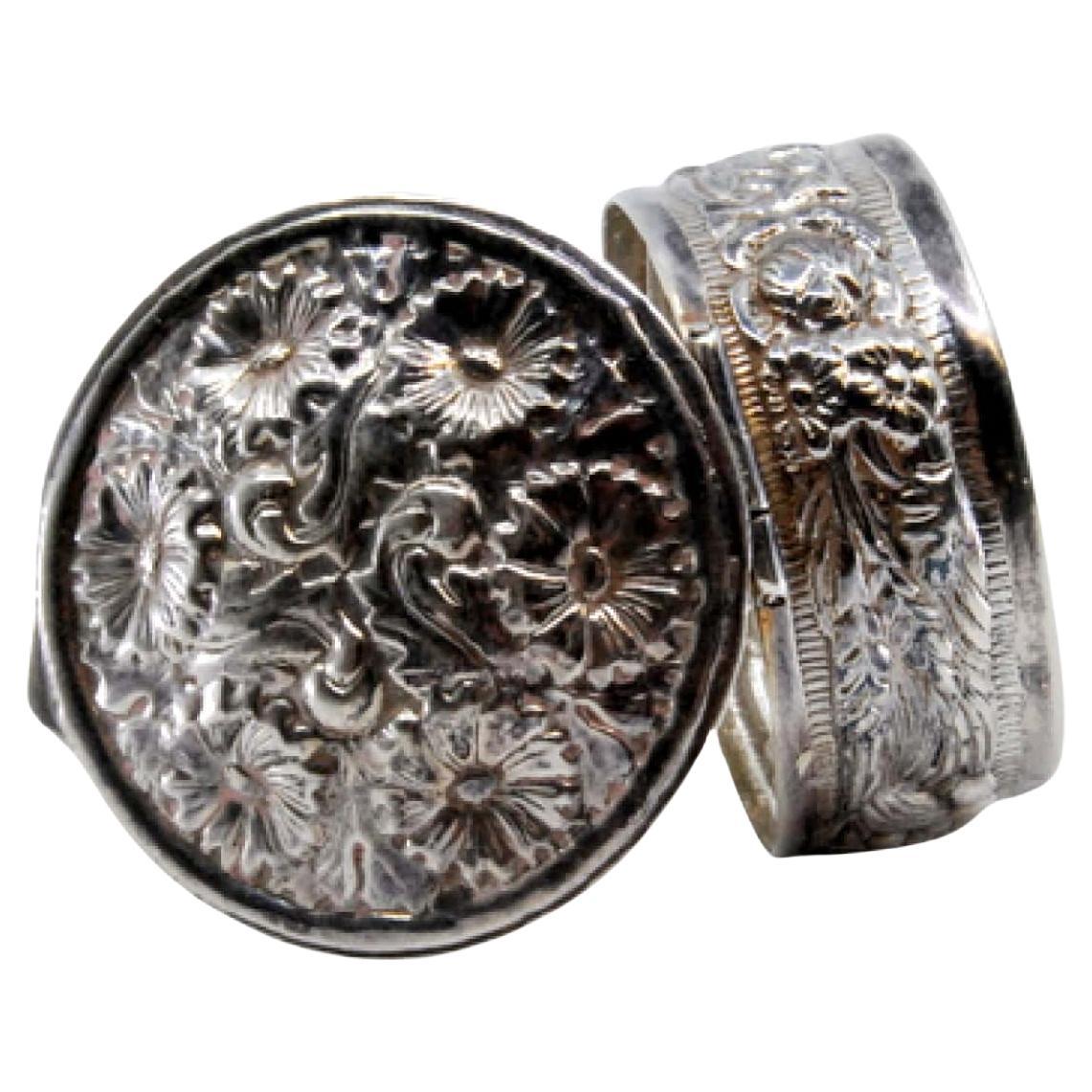 Circular silver pill box with relief plant motifs and hinged lid