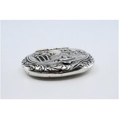 Circular silver pill box with reliefs and a hinged lid