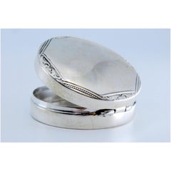 Circular silver pill box with trim on the hinged lid