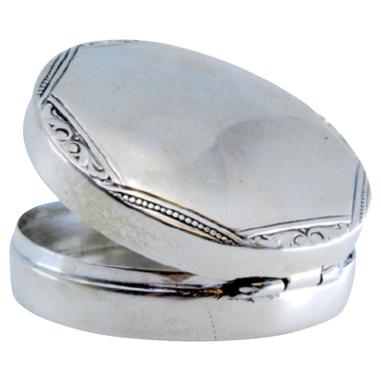 Circular silver pill box with trim on the hinged lid