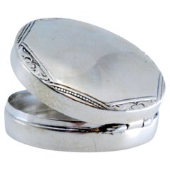 Circular silver pill box with trim on the hinged lid