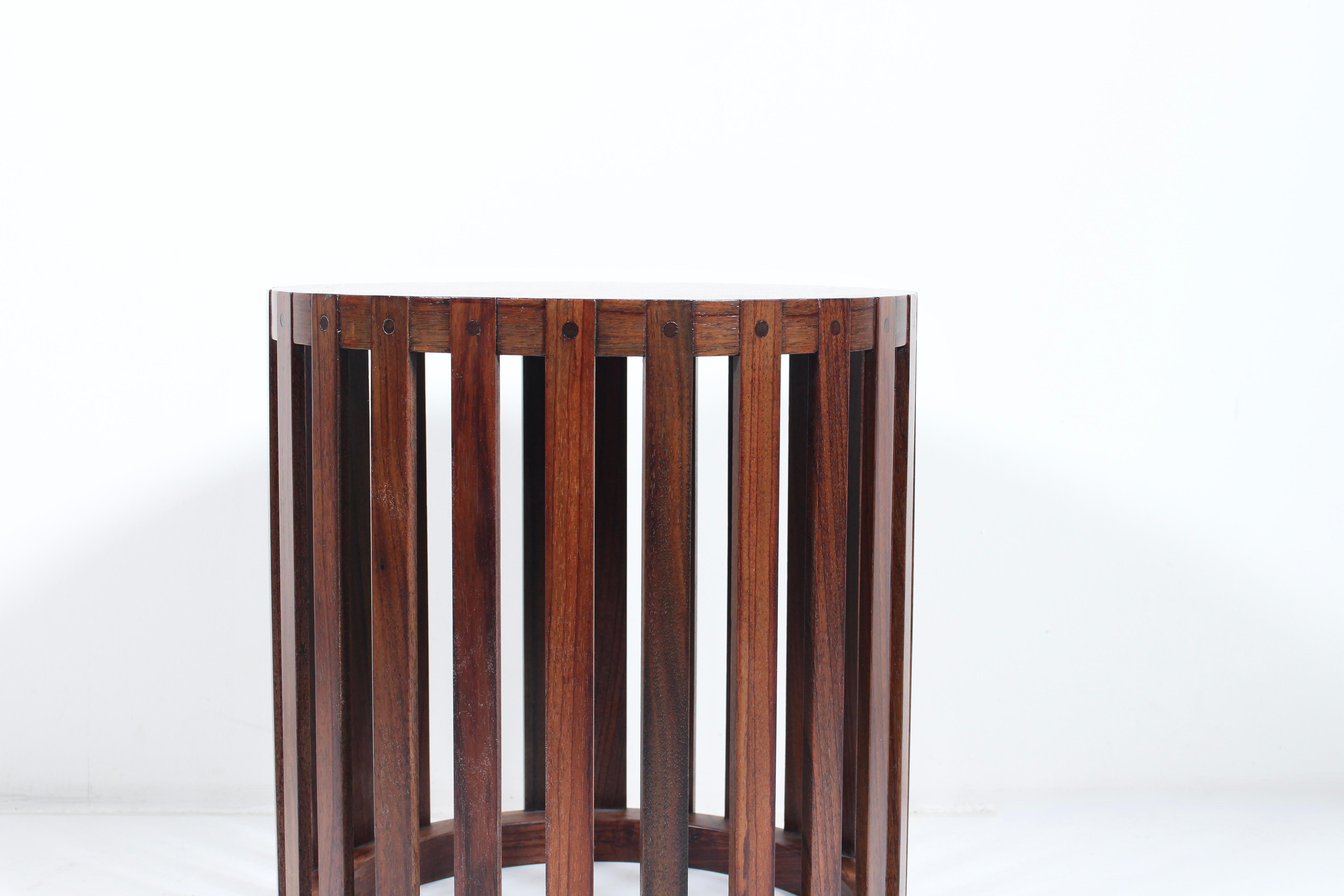 1960's Metropolitan Furniture Corp. round slatted and pegged solid rosewood occasional, side, end table. Featuring a solid Rosewood compact, drum style framework with slatted sides, attached top and bottom rings with wooden pegs. Timeless.