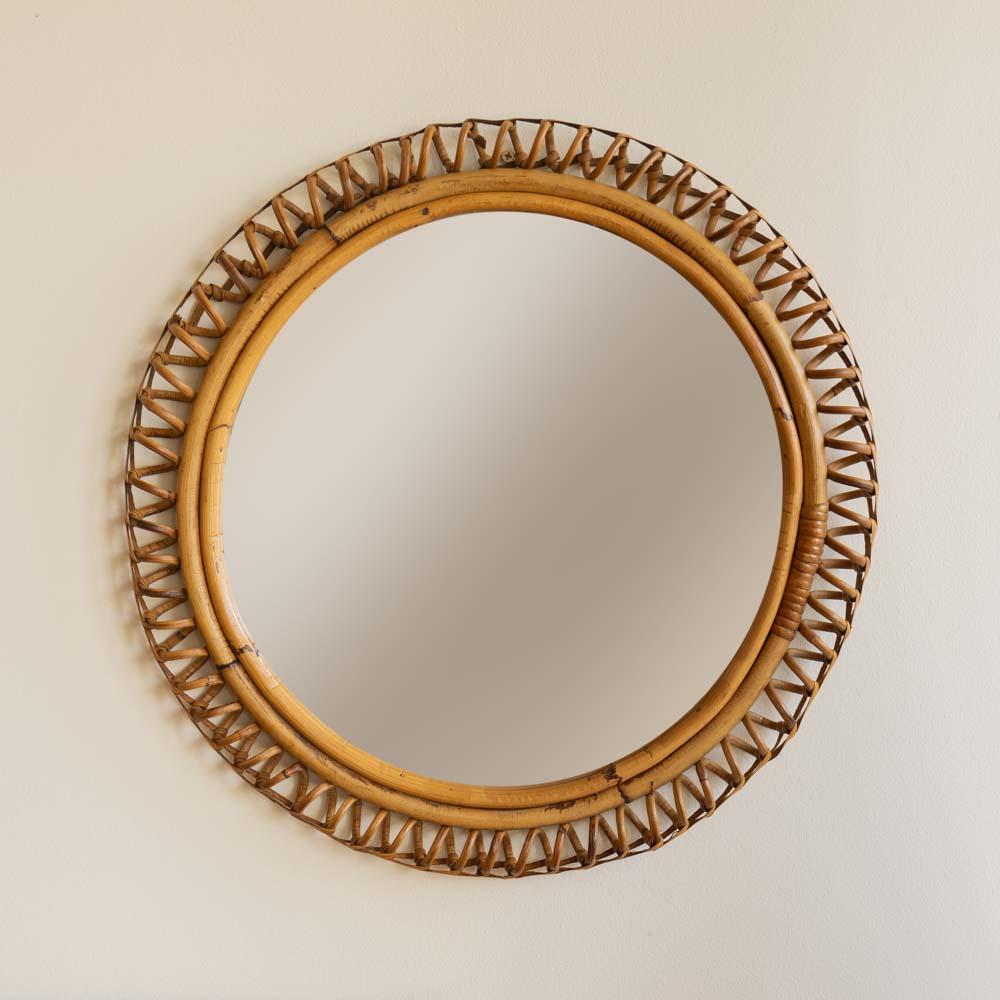 Beautiful circular rattan mirror from Italy, 1960's. Unique design with spiral rattan detailing encompassing the mirror. Original mirror and finish show nice age and patina. 