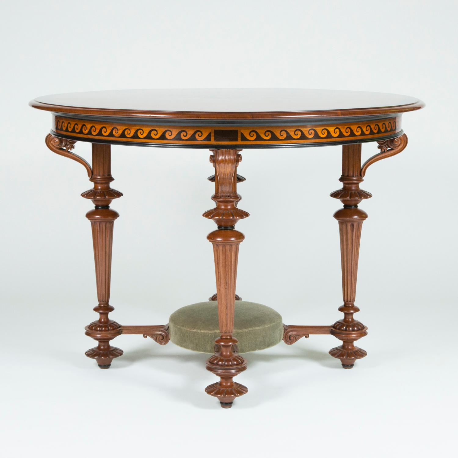 A fine quality circular carved walnut table inlaid with classical motifs. 

The top is veneered in burr walnut with a central marquetry 8 pointed star surrounded by palmettes radiating out to floral swags enclosed by a ebonized band. The turned