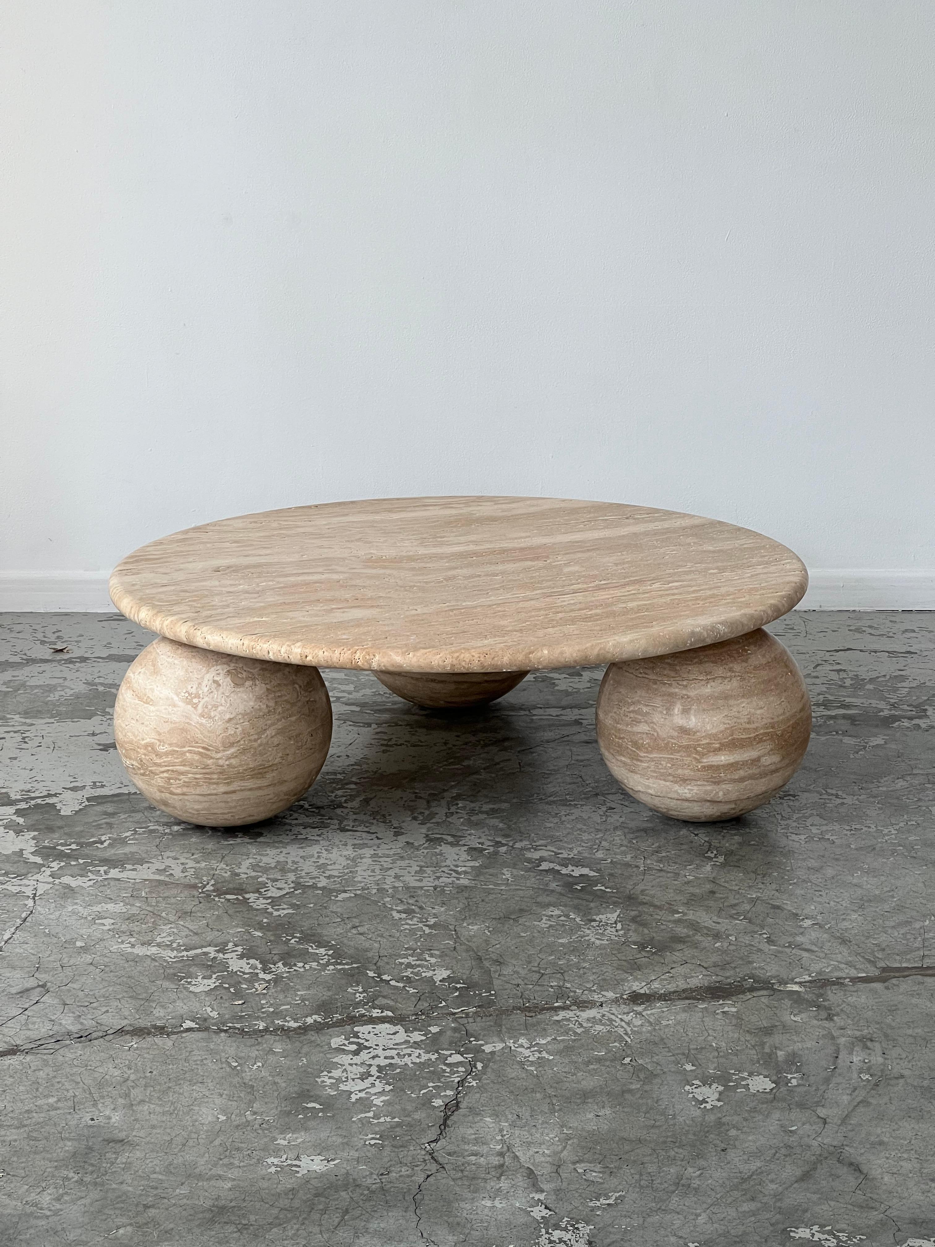 Table in untreated natural travertine. The overall structure is in travertine. The circular top rests directly on three solid spheres.
 