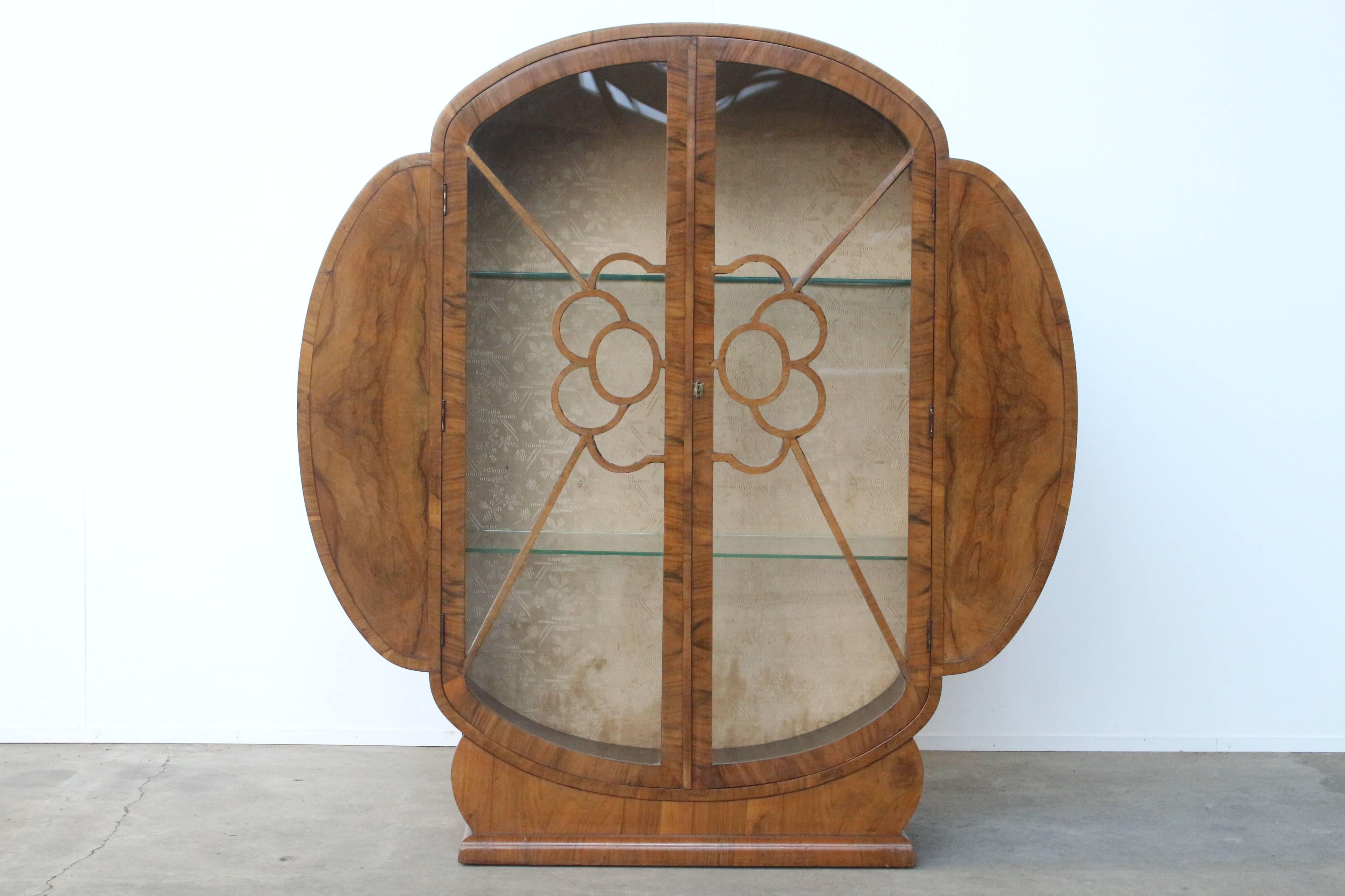 Stunning circular art-deco display cabinet in walnut with three glass shelves. The astragal doors show a beautiful cloud-shaped pattern and all the details are truly master crafted. The interior features the original silk showing a floral,