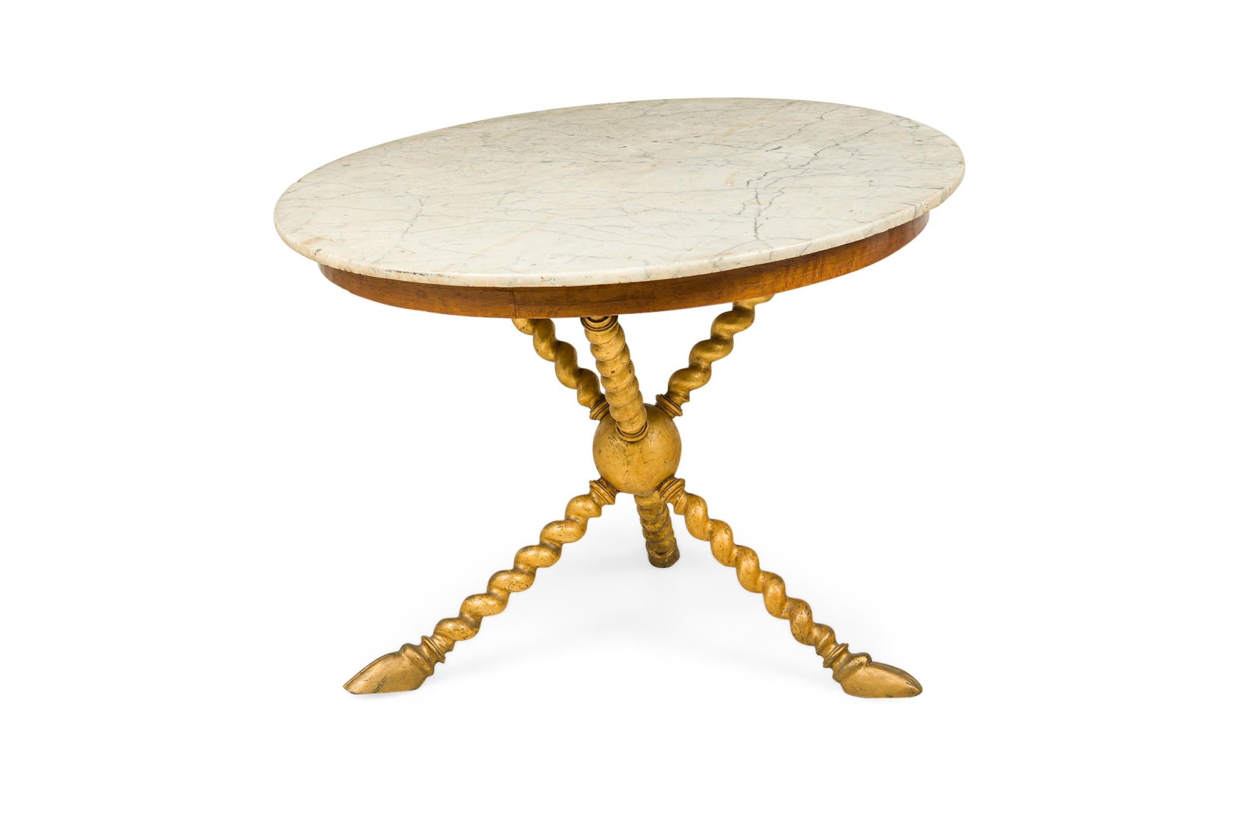 Mid-Century walnut circular center table with a painted gilt finish, an off-white marble top featuring gray striations, supported by 3 twisted rope form posts anchored to a central sphere and resting on 3 legs terminating in hoof feet.
 

 Wear to