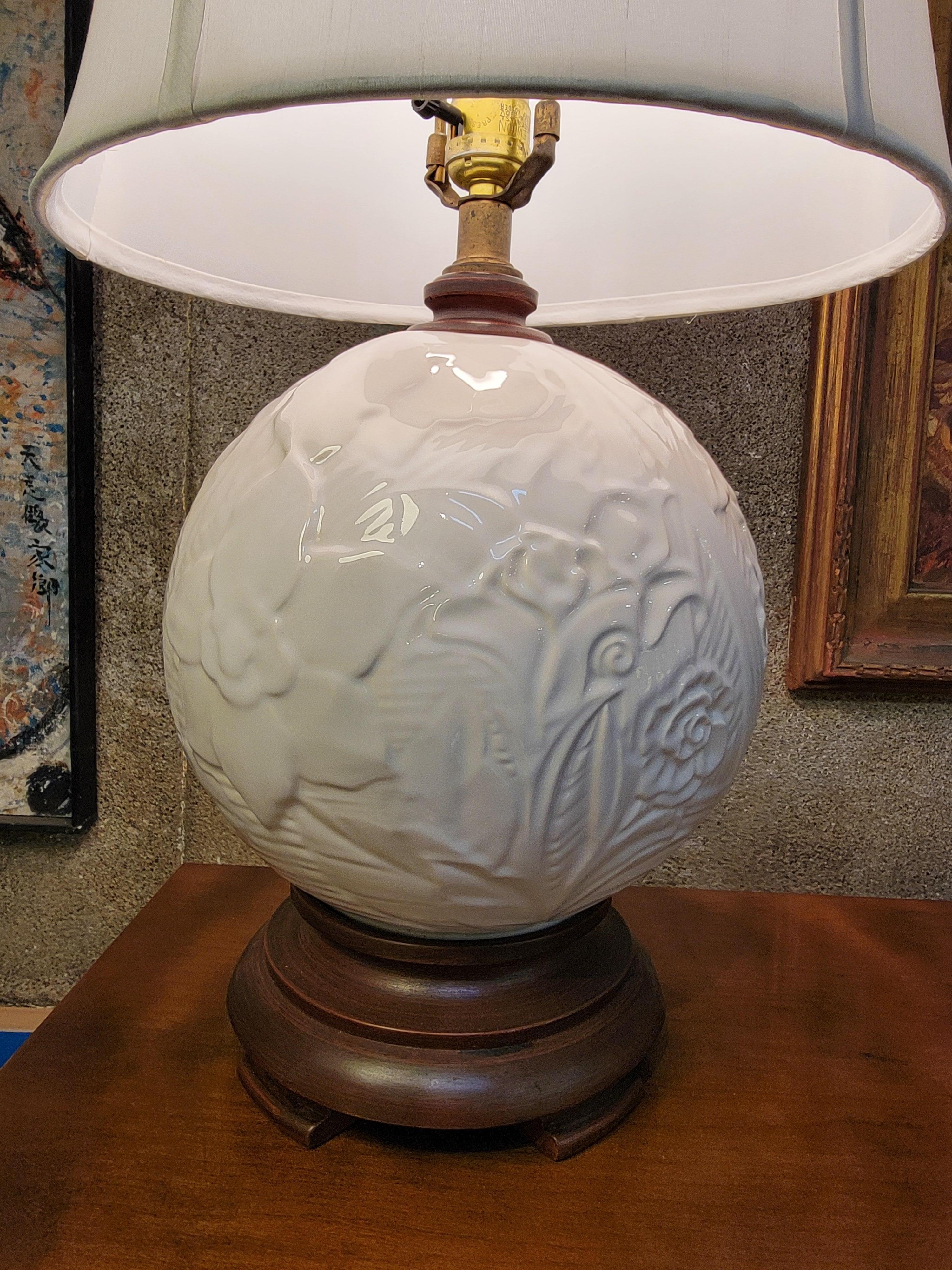 Lampada da tavolo in ceramica bianca con paralume di Haeger Pottery. Circa. 1960. Motivo floreale modellato sulla sfera di ceramica. Montato su una base di legno. Presa di corrente a 3 vie.

