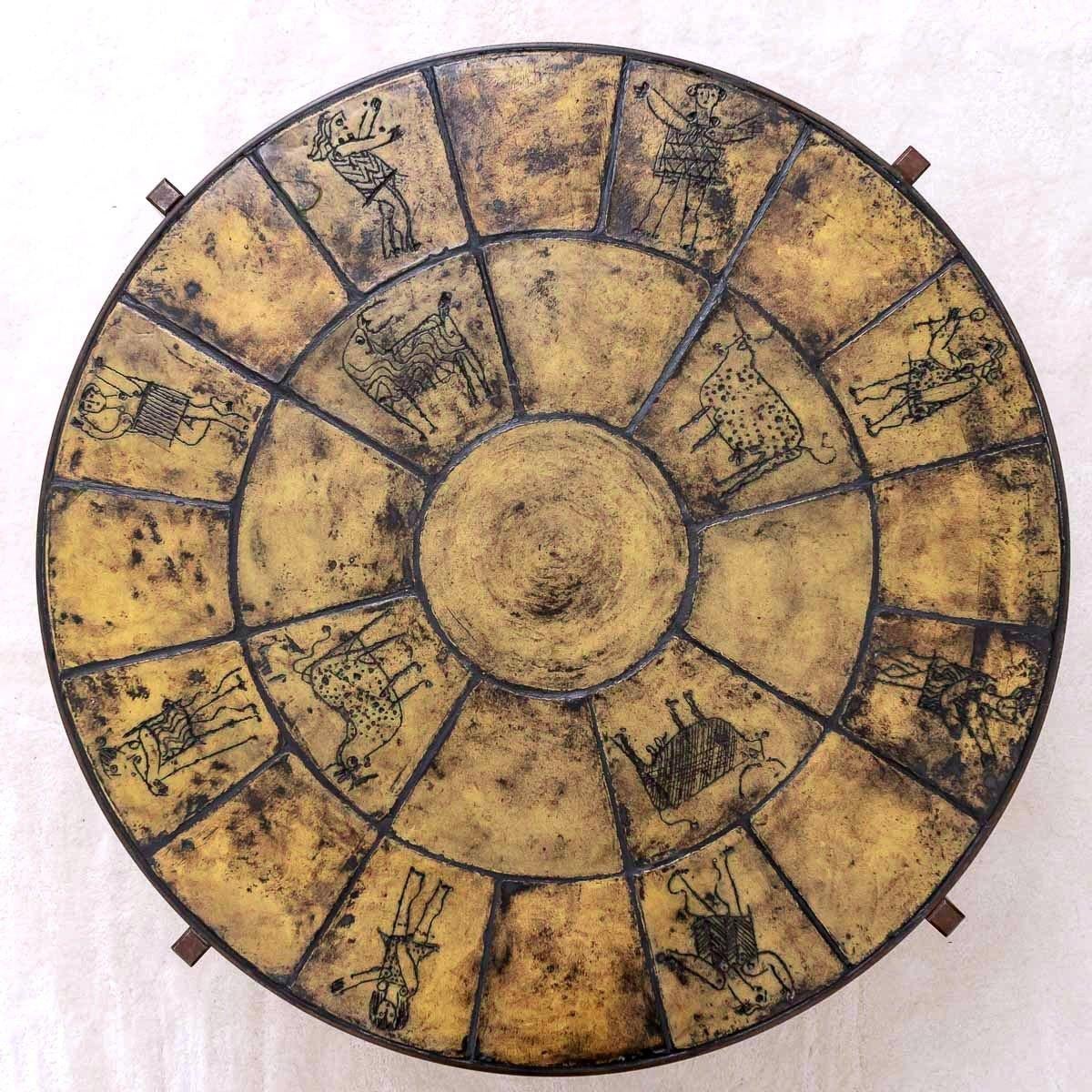 Rare coffee table with a circular wrought iron body with four square legs and a top decorated with 25 chiseled glazed ceramic tiles, 12 of which are illustrated with human and animal figures. 
The illustrations were engraved in a rather dry material
