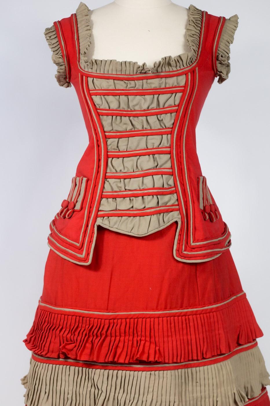Circa 1890
United States

Fancy Dress, skirt and bodice for circus, sport (?) or simply American commemoration (?) in vermilion red and grey woolen cheesecloth. Dress in two parts, sleeveless bodice, boat neckline, buttoning in front and cream