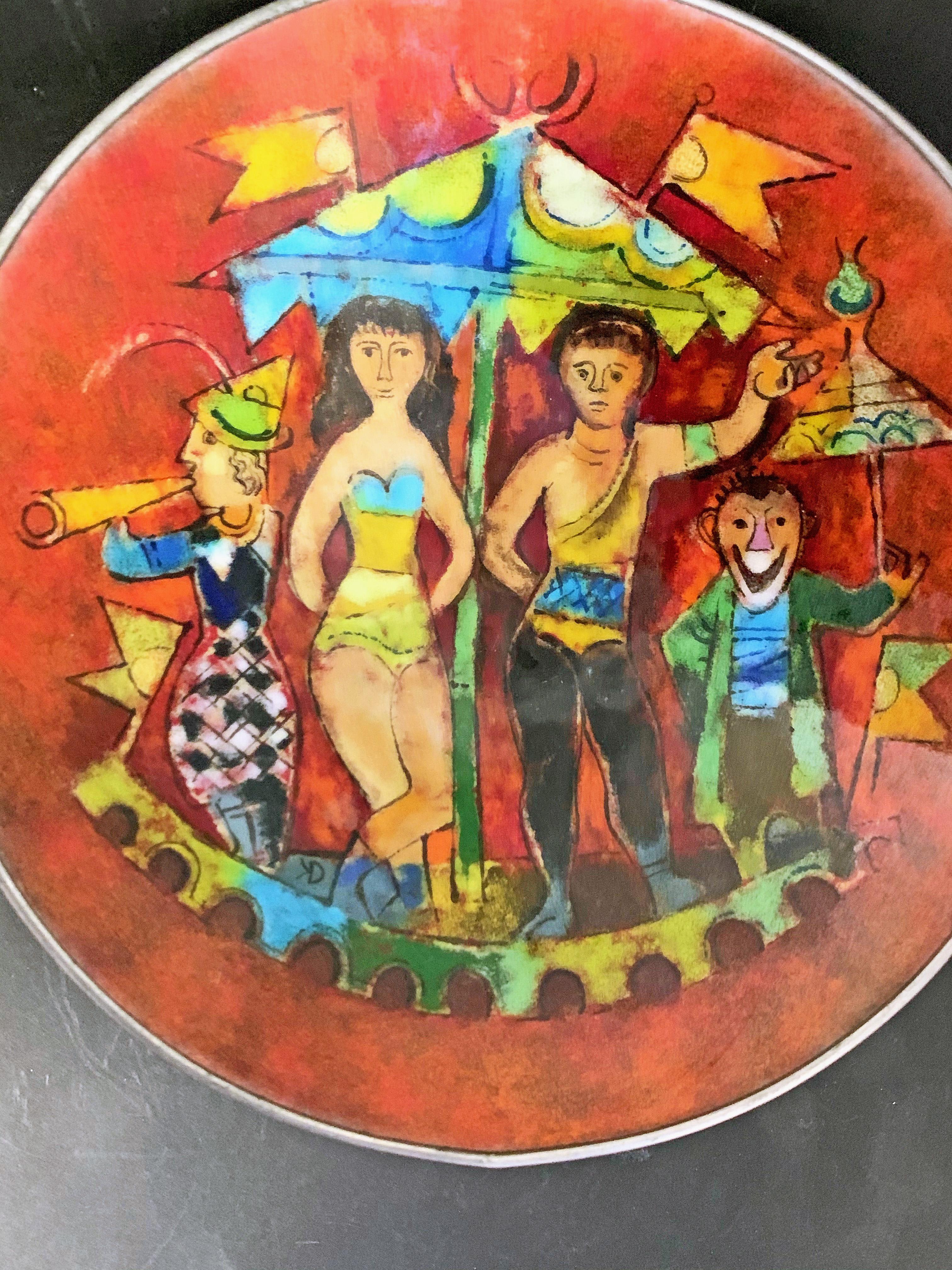 Diese Emaille-Schale in leuchtenden Farben, die eine Zirkusszene mit Trapezkünstlern, Musikern und Clowns zeigt, ist ein Meisterwerk der Emaille-Kunst aus der Mitte des Jahrhunderts. Sie wurde von dem berühmten Emaillekünstler Karl Drerup