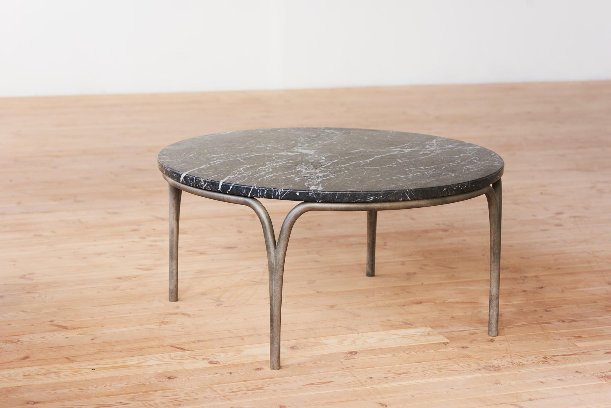 La table basse Cirrus juxtapose la solidité structurelle à la légèreté de la forme. La forme gracieuse des pieds crée une ouverture lorsqu'elle rencontre la masse du plateau de la table, l'espace négatif mettant en valeur les qualités distinctes de