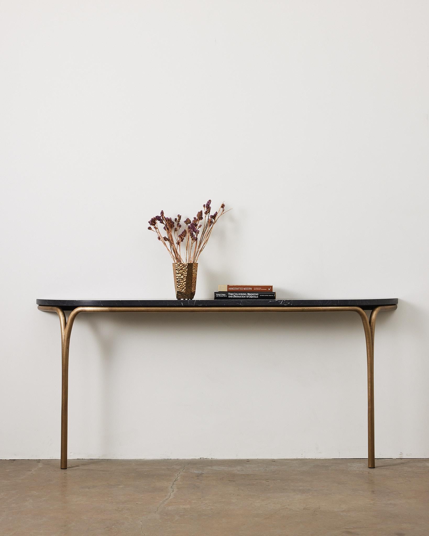 La table console Cirrus juxtapose la solidité structurelle à la légèreté de la forme. La forme gracieuse des pieds crée une ouverture lorsqu'elle rencontre la masse du plateau, l'espace négatif mettant en valeur les qualités distinctes de chaque
