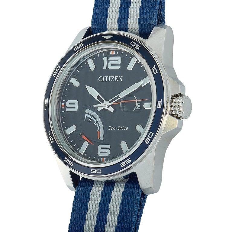 This is the Citizen PRT Eco-Drive watch, reference number AW7038-04L. It is presented with a 42 mm stainless steel case that is mounted onto a blue and gray nato strap, secured on the wrist with a tang buckle. The blue dial features central hours,