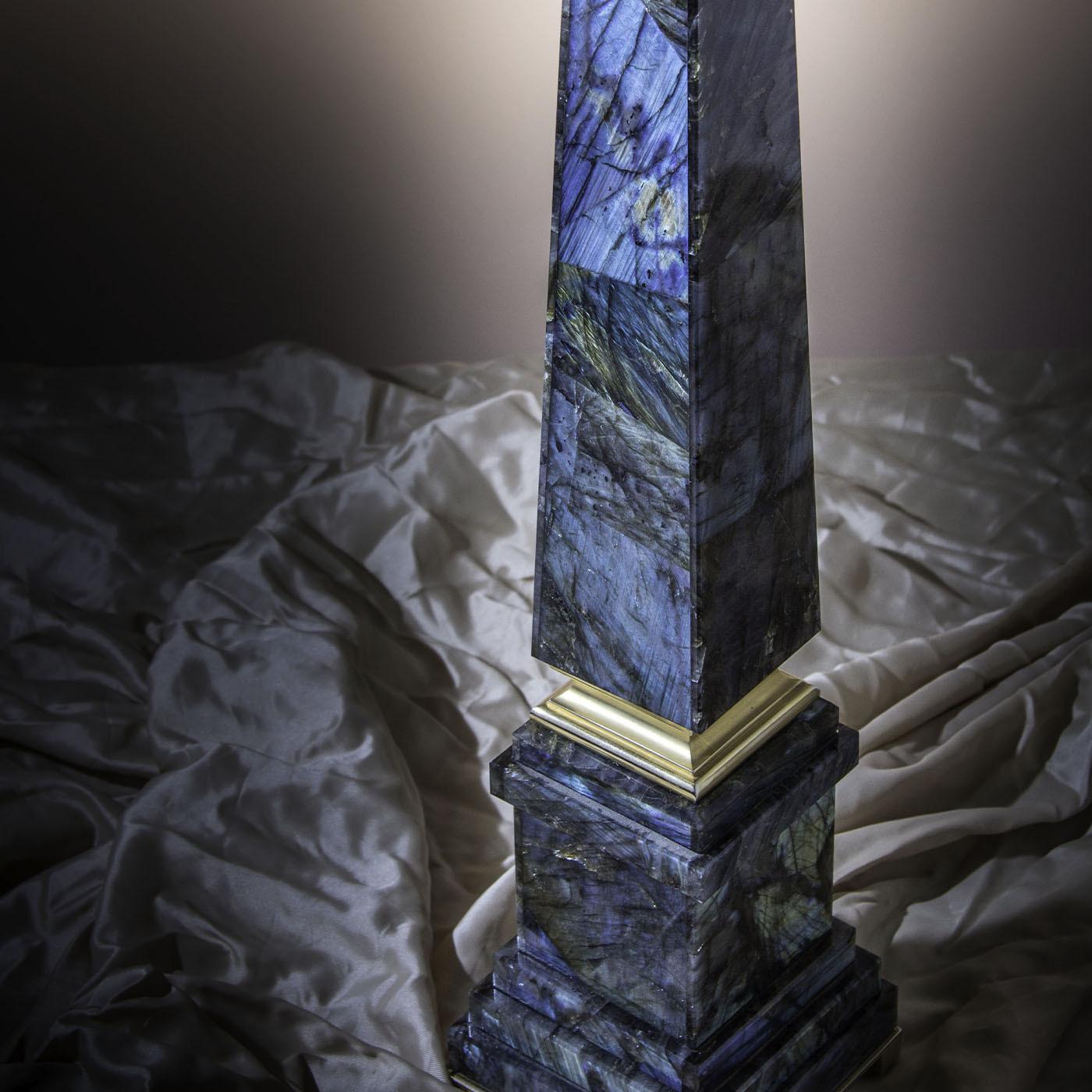 Questa scultura a forma di obelisco in preziosa labradorite si ispira agli obelischi gemelli di Roma e Istanbul. Magistralmente scolpita e arricchita da dettagli in ottone di lusso, la sua silhouette è dovuta a una specifica tecnica di mosaico che