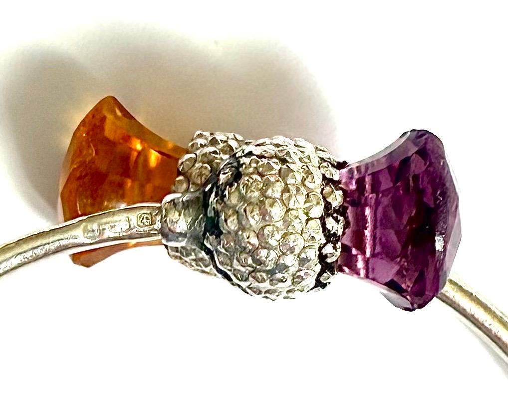 Wunderschöner Armreif aus 925er Silber mit Distelmotiv und einem Amethyst- und einem Citrinstein. Das Distel-Element ist aus strukturiertem Silber und verbindet sich mit dem Armreif mit den beiden Edelsteinen auf beiden Seiten. Der Amethyst hat ein