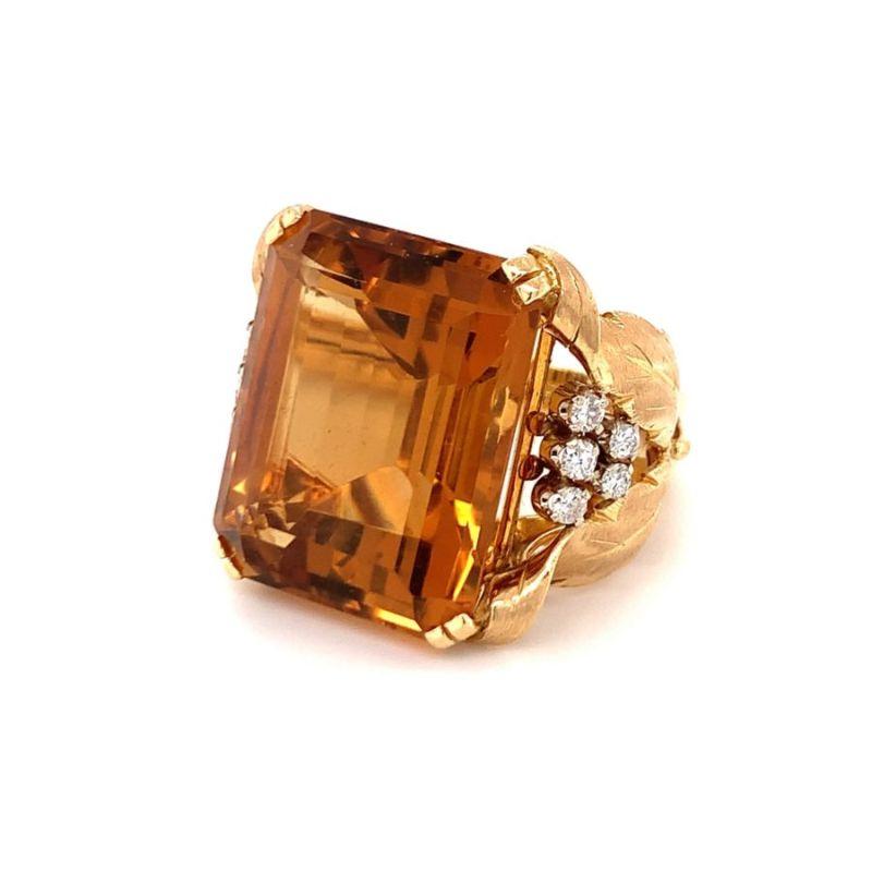 One citrine and diamond 18K yellow gold leaf motif ring centering one prong set, emerald cut citrine weighing approximately 40 ct. (24 x 20 mm.) flanked by ten transitional round brilliant cut diamonds weighing approximately 0.45 ct. Circa
