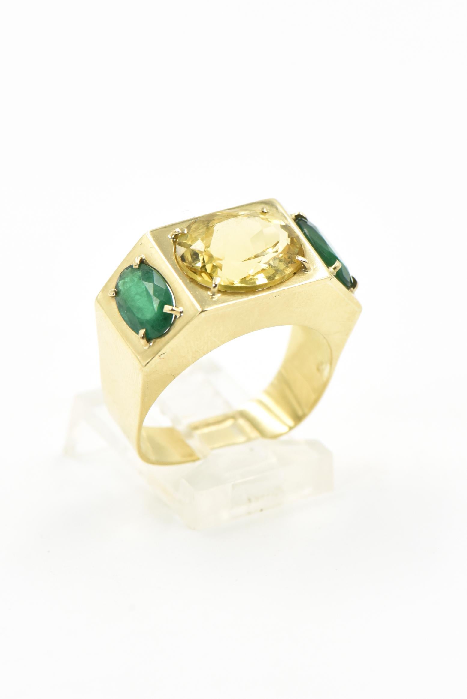 Elegant 3 stone ring featuring a prong set faceted oval citrine approximately 4 carats set east to west.  On either side, prong set north to south is an emerald that weights approximately .90 carat each.  The three stones are mounted in a