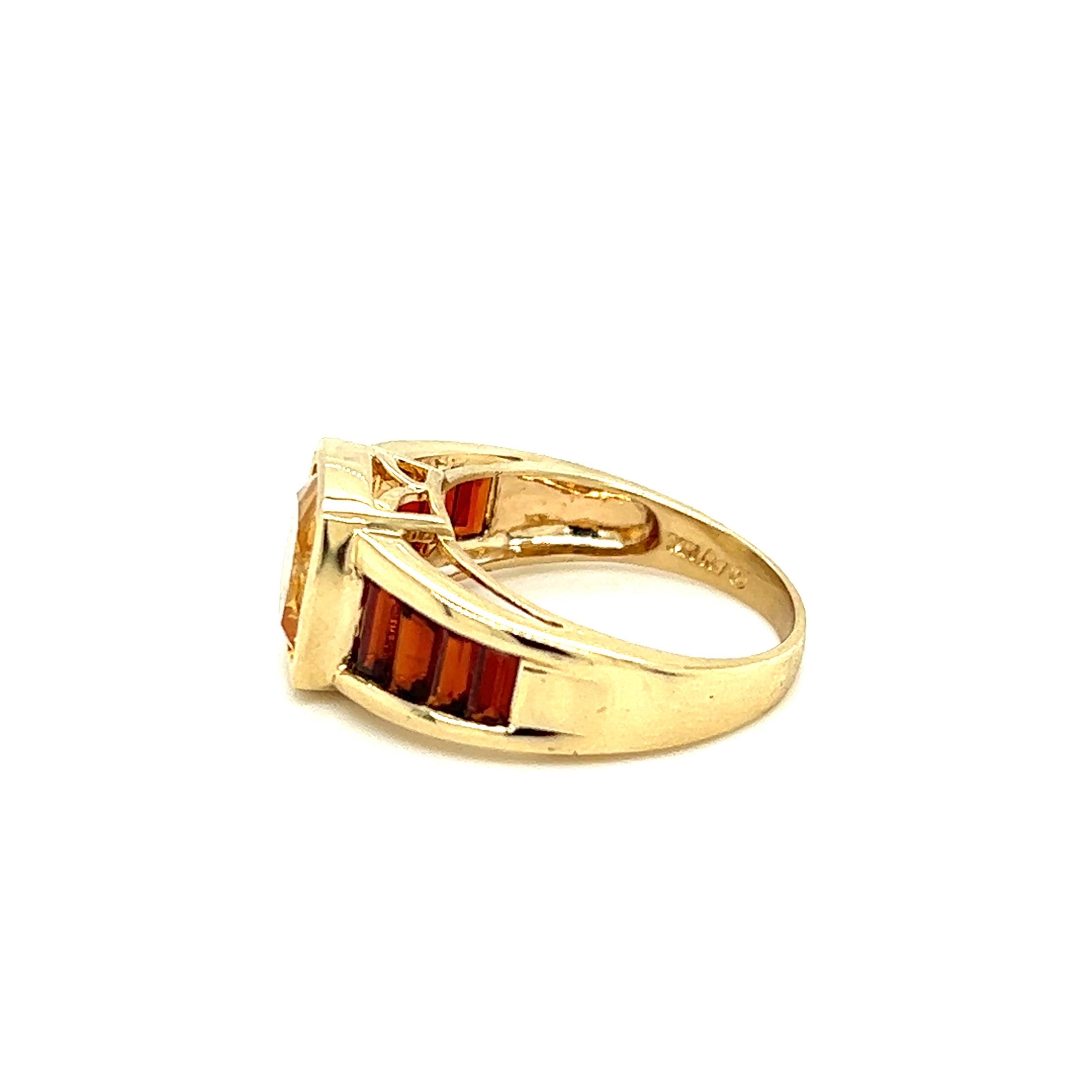 One 14-karat yellow gold (stamped 14K 98) ring set with one 9mm cushion cut citrine, flanked by eight (8) baguette-cut red garnets, ranging in size from 3.5mm to 5.5mm. The ring measures 10.70mm at the top of the ring and tapers to 2.90mm at the