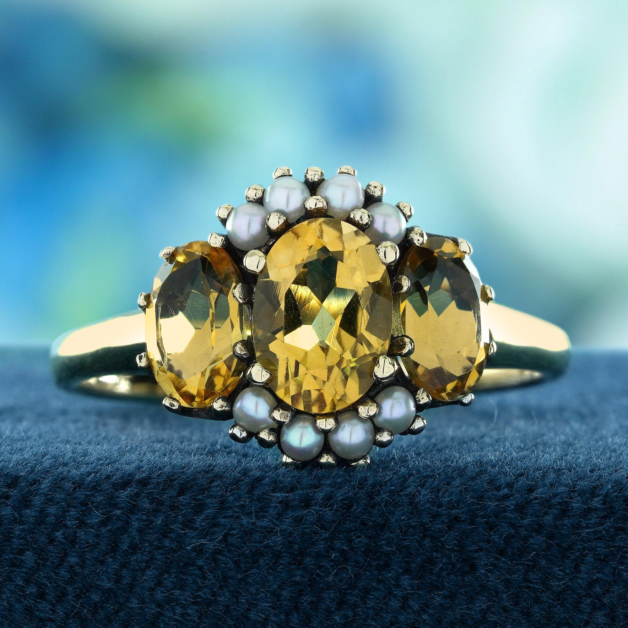 Ein strahlendes Fest der Eleganz und Wärme. Die drei goldenen Zitrinen symbolisieren mit ihren leuchtenden Farben Freude und Wohlstand und bilden einen schillernden Mittelpunkt. Glänzende Perlen akzentuieren das Design und verleihen ihm einen Hauch