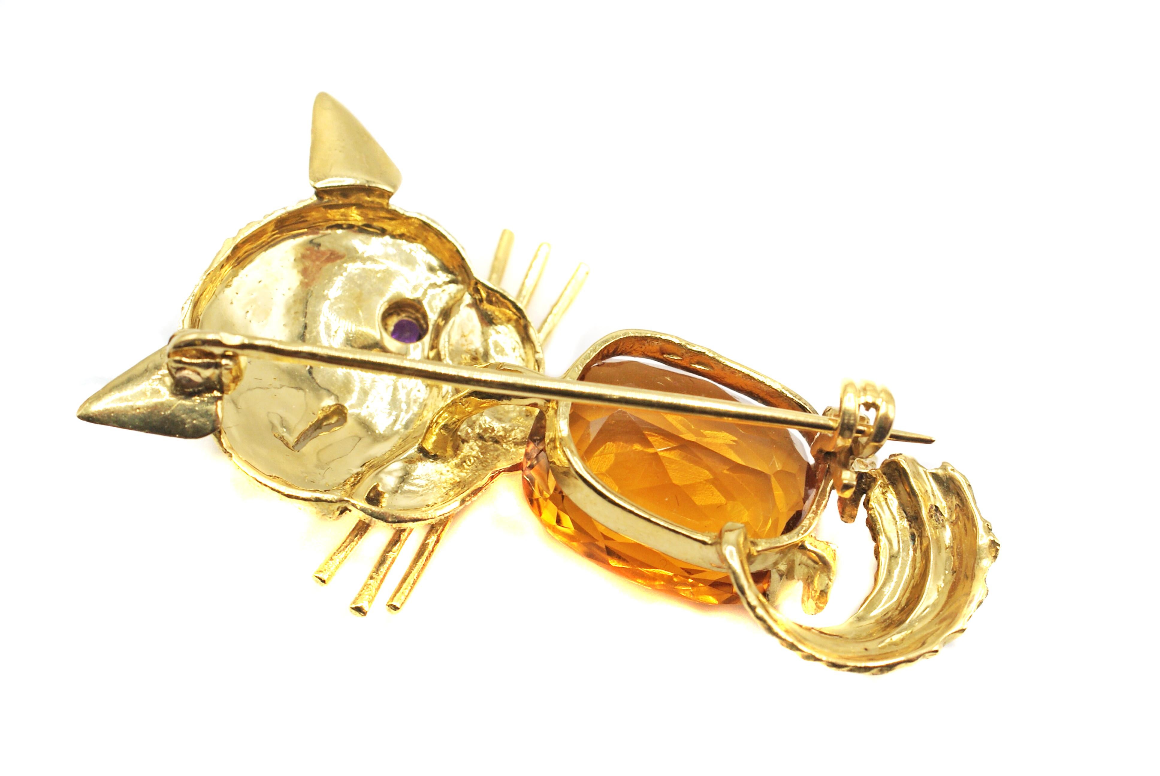The bright orange citrine center of this brooch is approximately 7 carats. The beautiful cut of this oval cushion bring this gem to life and represents the body of this delightful whimsical cat brooch. The textured and beautifully engraved face of