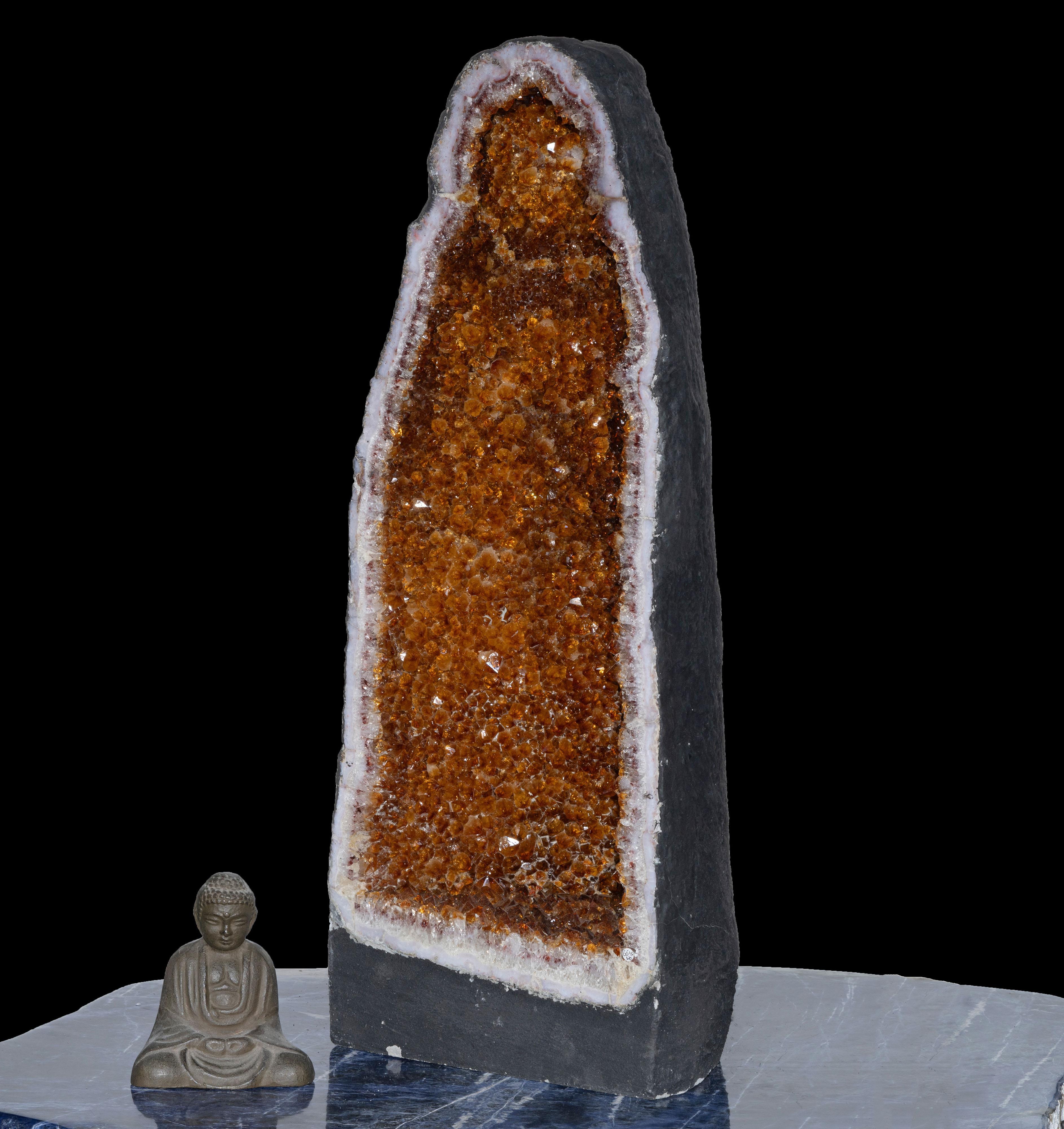 This over two foot tall sinuous citrine cathedral from Brazil glistens from within with a lustrous coating of naturally terminated, fully formed, fiery amber citrine crystals. This substantial acquisition will add color and sparkle to any atmosphere