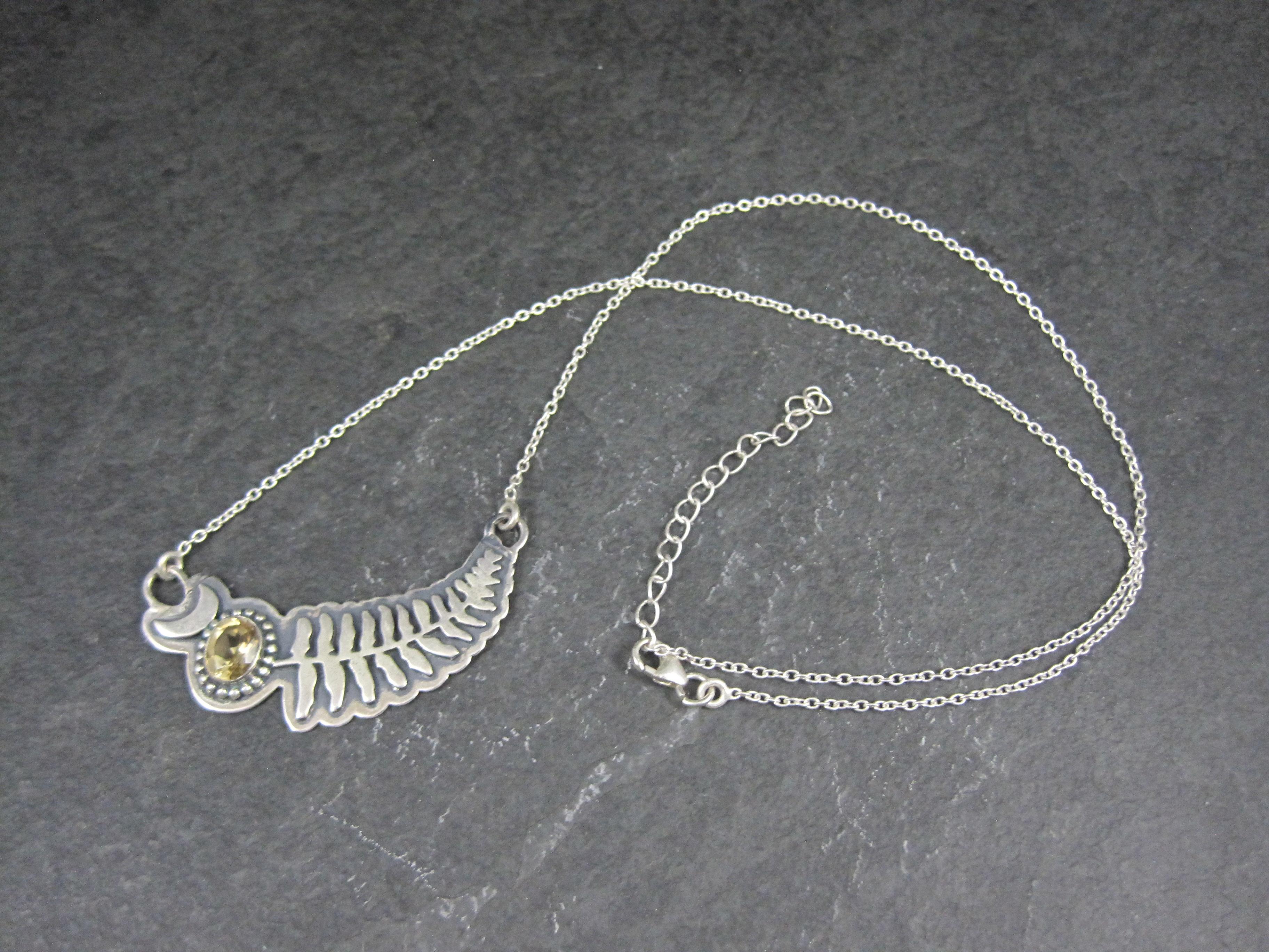 This beautiful pendant and chain necklace is sterling silver.
It features an oval cut 6x8mm citrine set in an overlaid design of crescent moon and fern leaf.
The pendant measures 5/8 by 2 inches. The chain is 18 inches plus 2 inch
